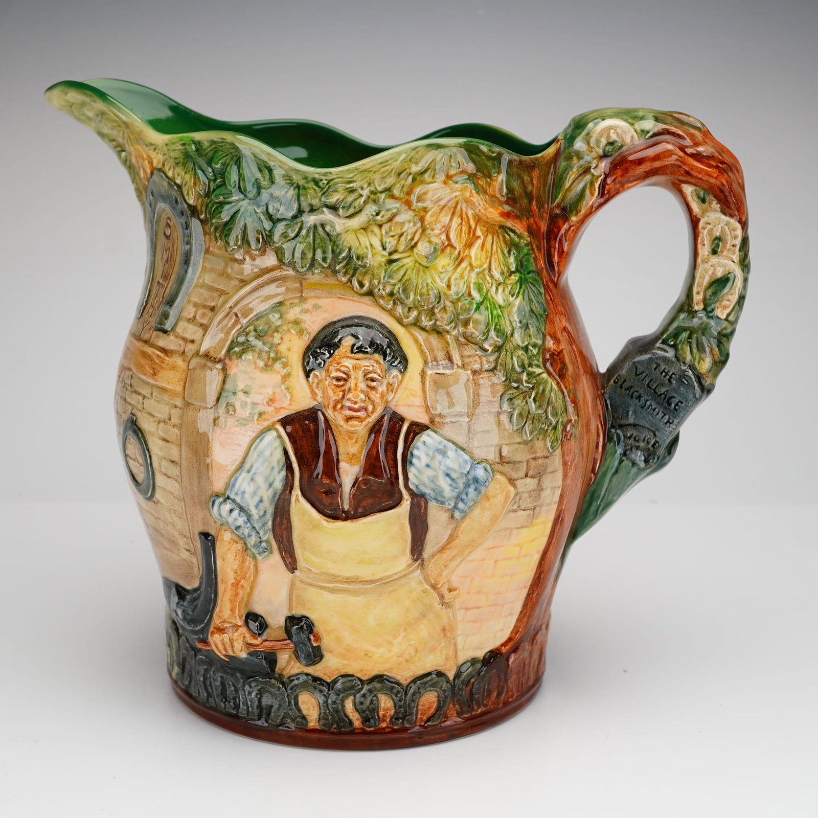 Royal Doulton Presentation Jug, The Village Blacksmith: A Royal Doulton relief-molded ceramic jug titled The Village Blacksmith, produced as a limited edition. The vessel features polychrome high-relief scenes inspired by the 1842 poem by Henry Wadsworth L