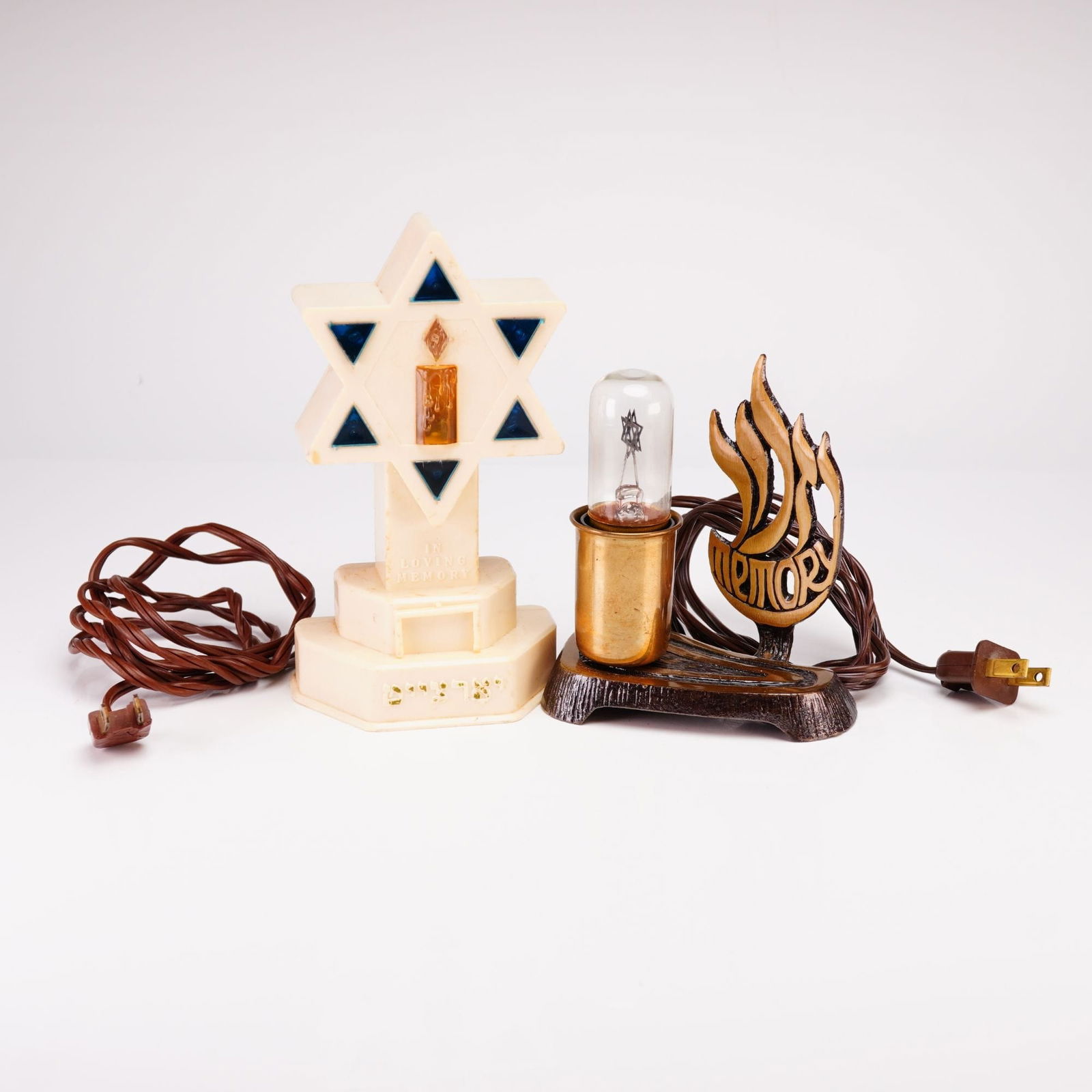 American Mid-20th Century Electric Yahrzeit Memorial Lamps, Pair: A 2pc Judaica grouping including two Yahrzeit memorial lamps. The first is an American mid-20th-century electric memorial lamp constructed of ivory-toned molded plastic. The design features an Art Dec