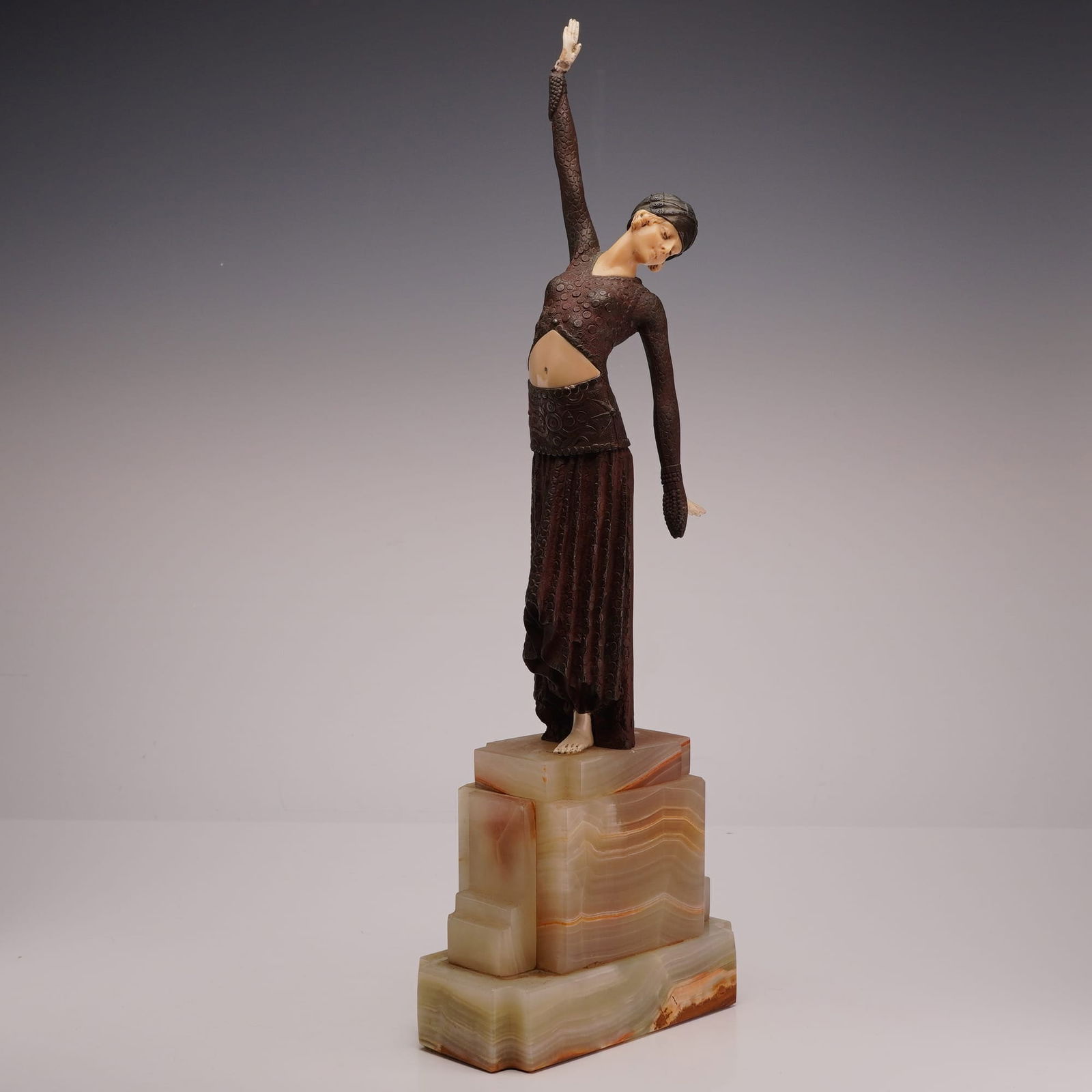After Demetre Chiparus Art Deco Style Patinated Bronze Sculpture on Onyx Base: Art Deco style chryselephantine sculpture in the manner of Demetre Chiparus, specifically resembling the Thais model. The figure is composed of patinated bronze with a dark brown finish, featuring a t