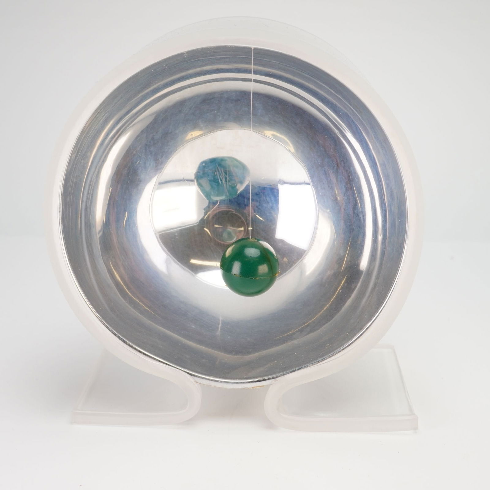 Mid-Century Modern Concave Mirror Sculpture: Featuring a polished chrome concave mirror mounted on a clear acrylic (lucite) stand. The design incorporates a suspended ball pendulum positioned within the mirror, creating dynamic optical reflectio