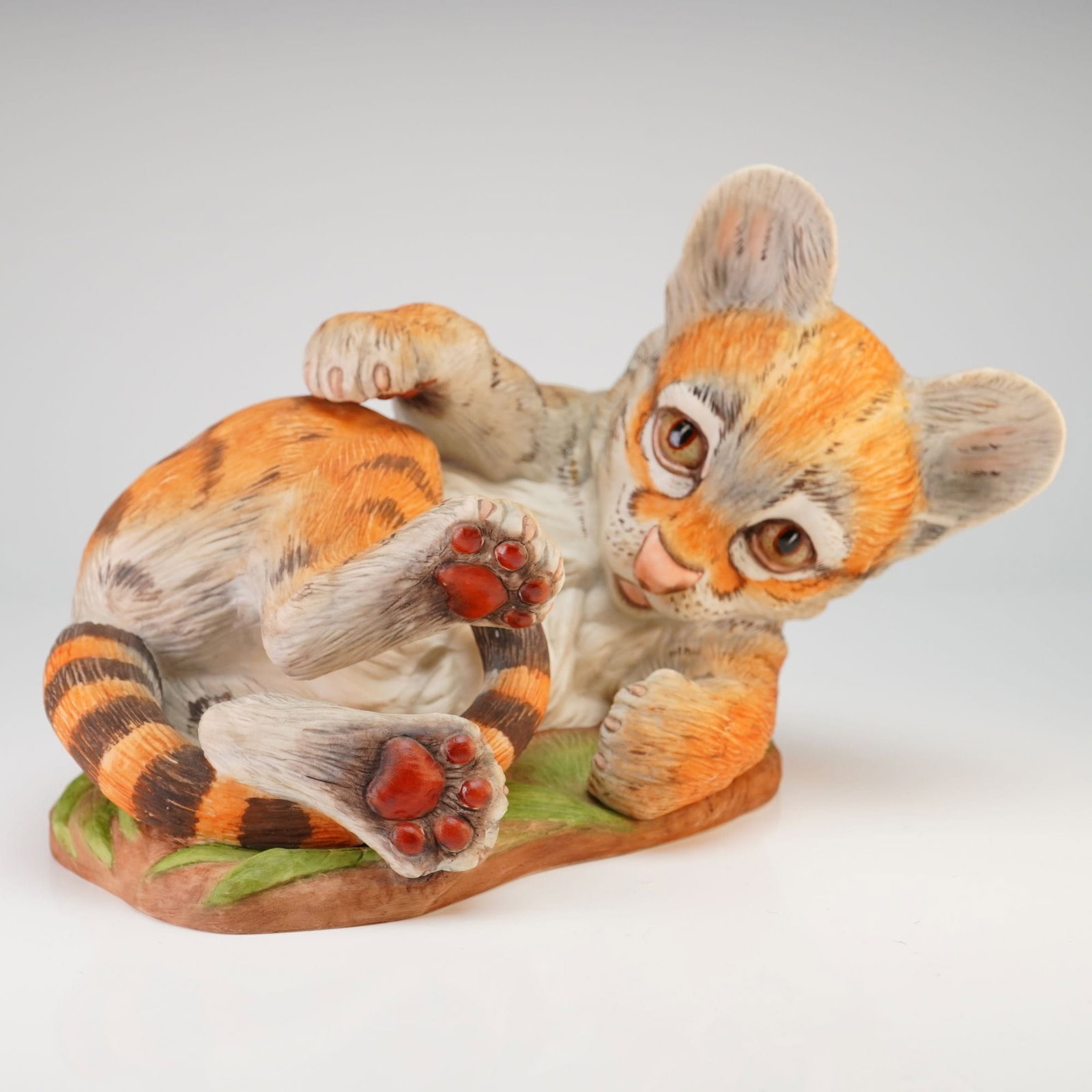 Edward Marshall Boehm Porcelain Baby Ocelot Figurine Model 400-40: This hand-painted bisque porcelain figurine is produced by Edward Marshall Boehm and depicts a baby ocelot cub. The animal is modeled in a reclining, belly-up pose on a low base textured and colored t