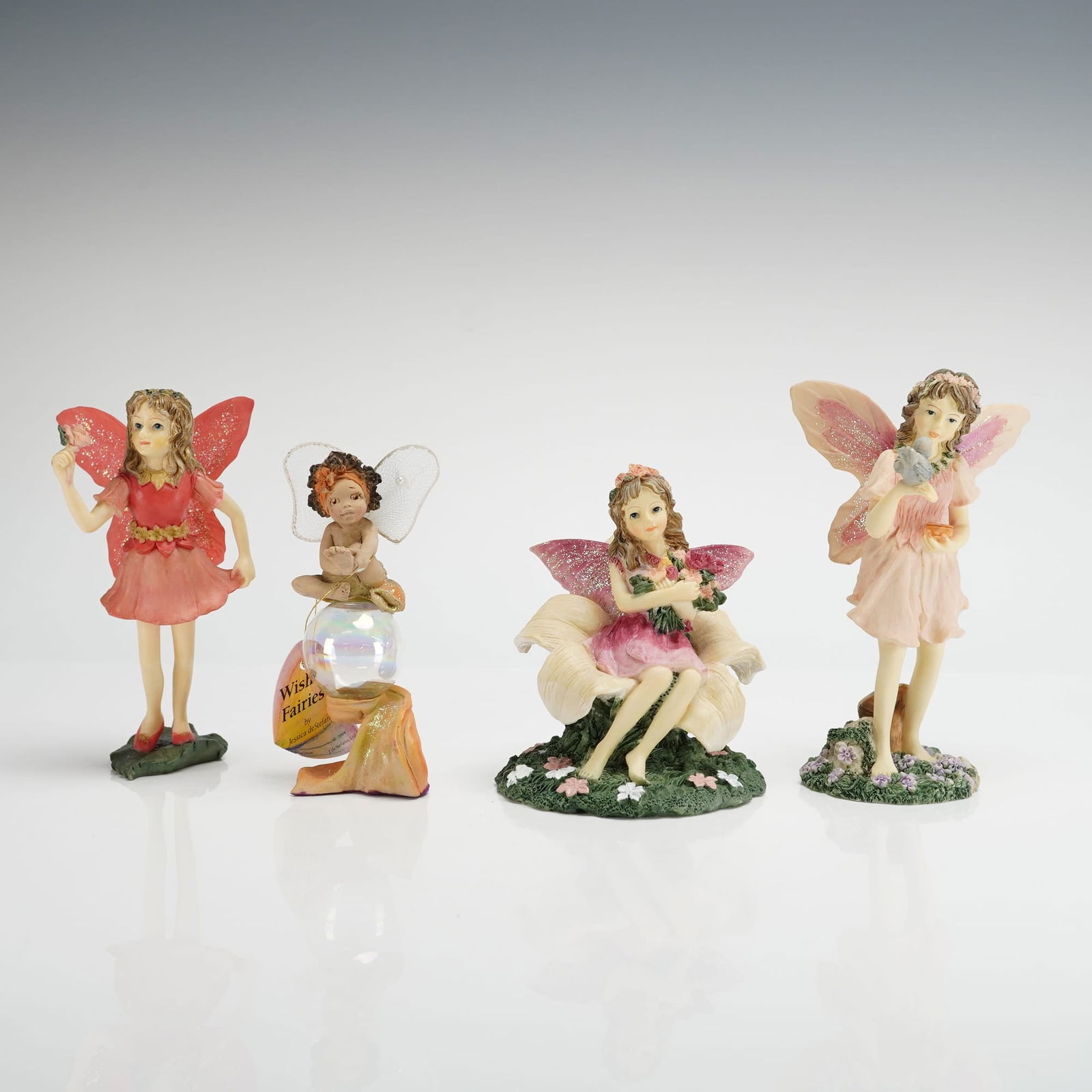 4 Dezine Fairy Figurines & Rawcliffe Wish Fairy Ornament: A collection of four collectible fairy figurines, primarily attributed to Dezine's "The Fairy Collection," dating to 1996. The lot includes four figurines, four original accompanying boxes, one small