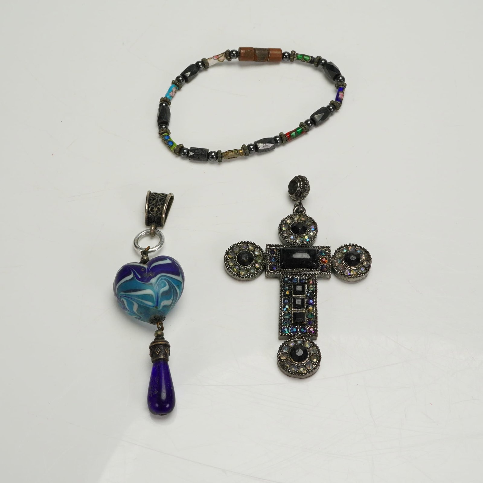 Trio of Costume Jewelry incl Rhinestone Cross Pendant: The collection consists of three pieces of contemporary costume jewelry. The primary piece is a large, ornate cross pendant. This cross pendant is crafted from darkened base metal, possibly with a gun