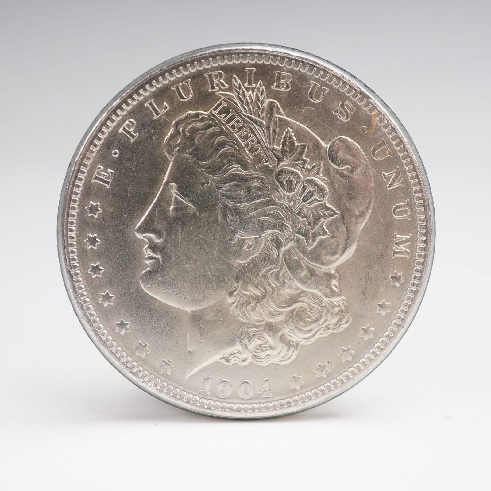 1904 Morgan Dollar Silver Coin New Orleans Mint Mark: The 1904 O Morgan Silver Dollar is struck in .900 fine silver, featuring the iconic profile of Lady Liberty on the obverse with a wreath and star design. The reverse depicts an eagle with wings spread