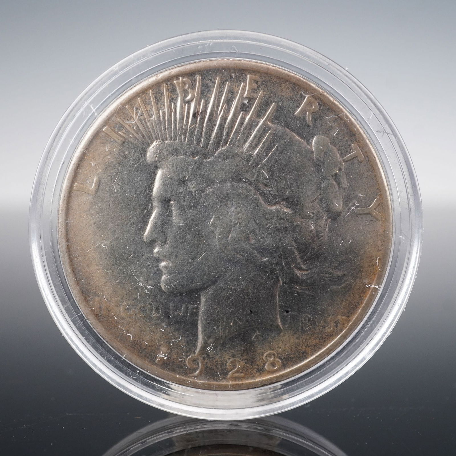 1928 Silver Peace Dollar: A 1928 Silver Peace Dollar, designed by Anthony de Francisci to commemorate the restoration of peace following World War I. The obverse features the profile of Lady Liberty wearing a radiant crown wit