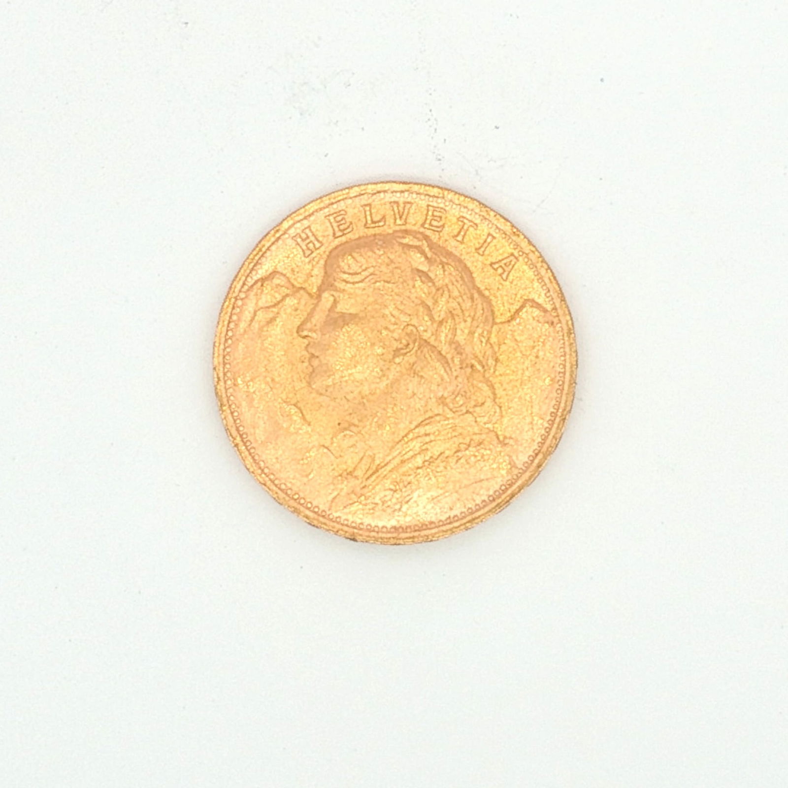 1947 Switzerland 20 Francs Vreneli Gold Coin: Minted by Bern, Switzerland. The obverse depicts bust of young woman left-facing with tresses and a garland of edelweiss. The reverse displays Coat of Arms and Oak (Quercus robur) branch with acorns a