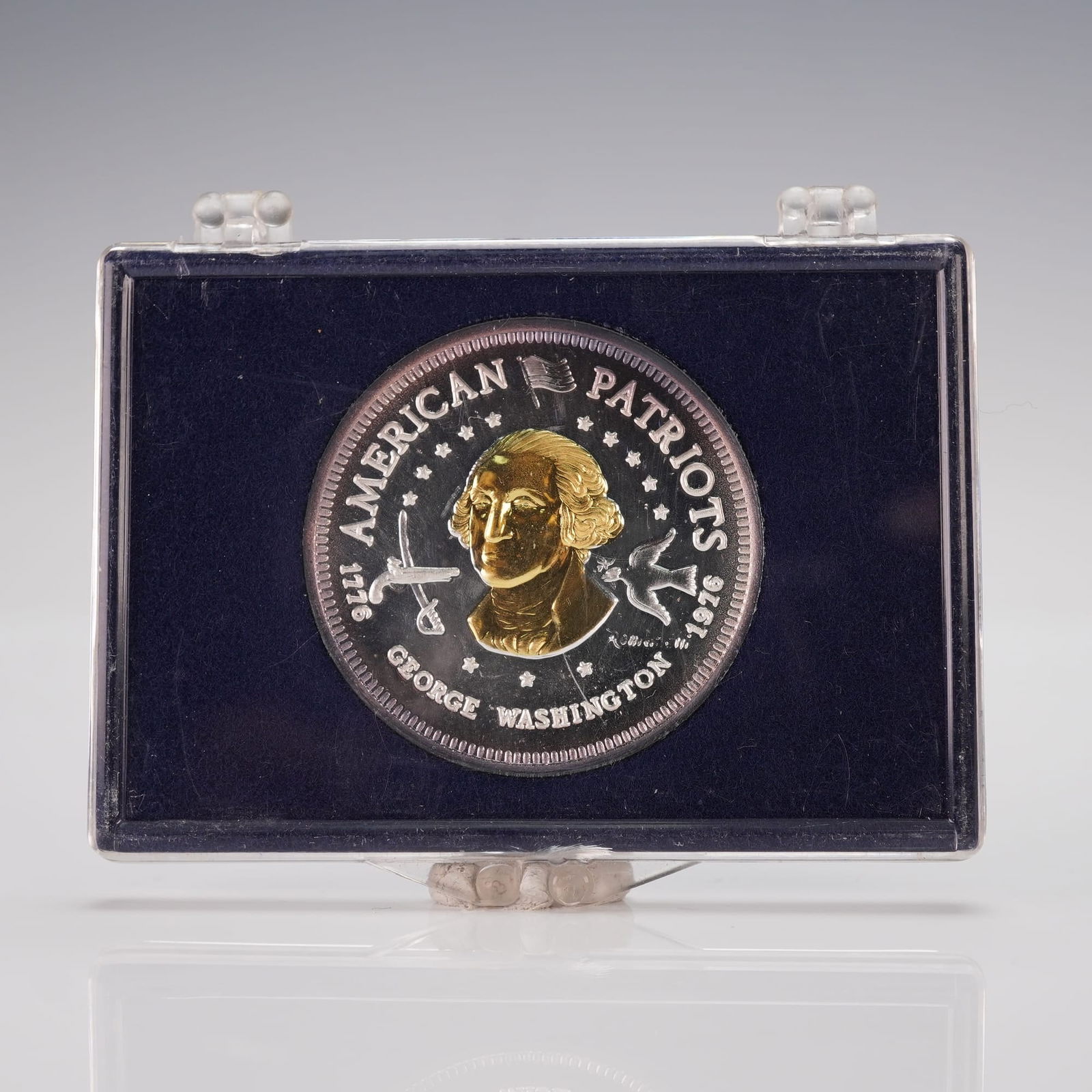1976-L George Washington American Patriots Silver and Gold Bullion: An obverse portrait of George Washington with surrounding inscriptions AMERICAN PATRIOTS, 1776, and 1976, accompanied by two stylized colonial-era weapons, and a reverse displaying a laurel wreath enc