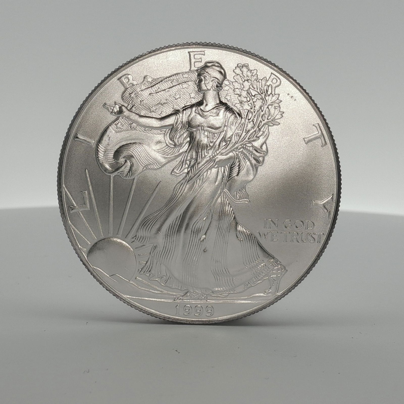 1999 American Silver Eagle One Dollar Coin: Minted by the Philadelphia Mint. The obverse side depicts an effigy of Walking Liberty with the date below. The reverse side depicts an heraldic eagle with shield and lettering United States of Americ