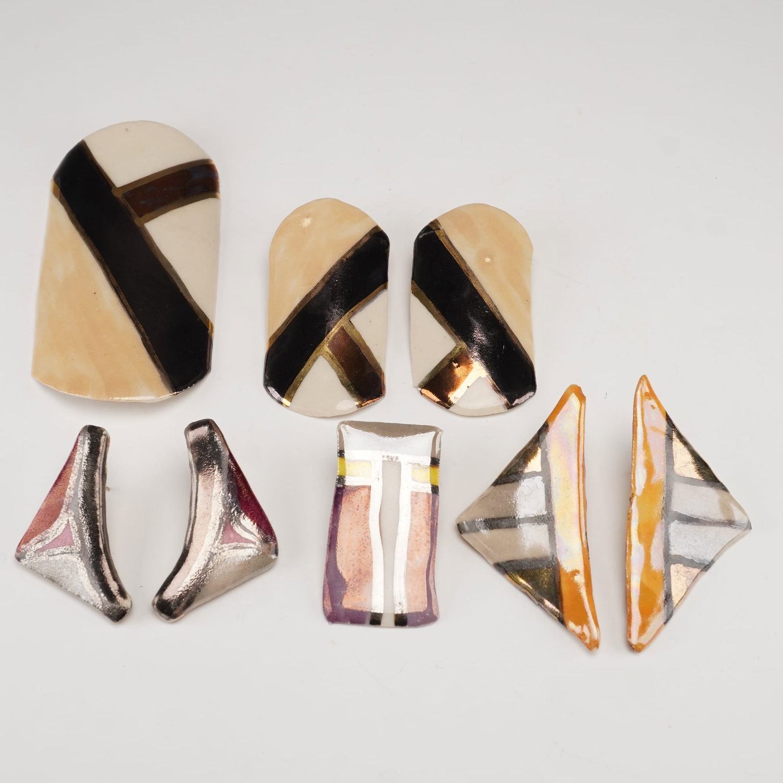 8pc Modernist Ceramic Earrings and Brooch: A group of 8 ceramic jewelry pieces featuring bold modernist designs with geometric patterns and metallic accents. Included are 3 complete sets of earrings, 1 single earring that visually complements