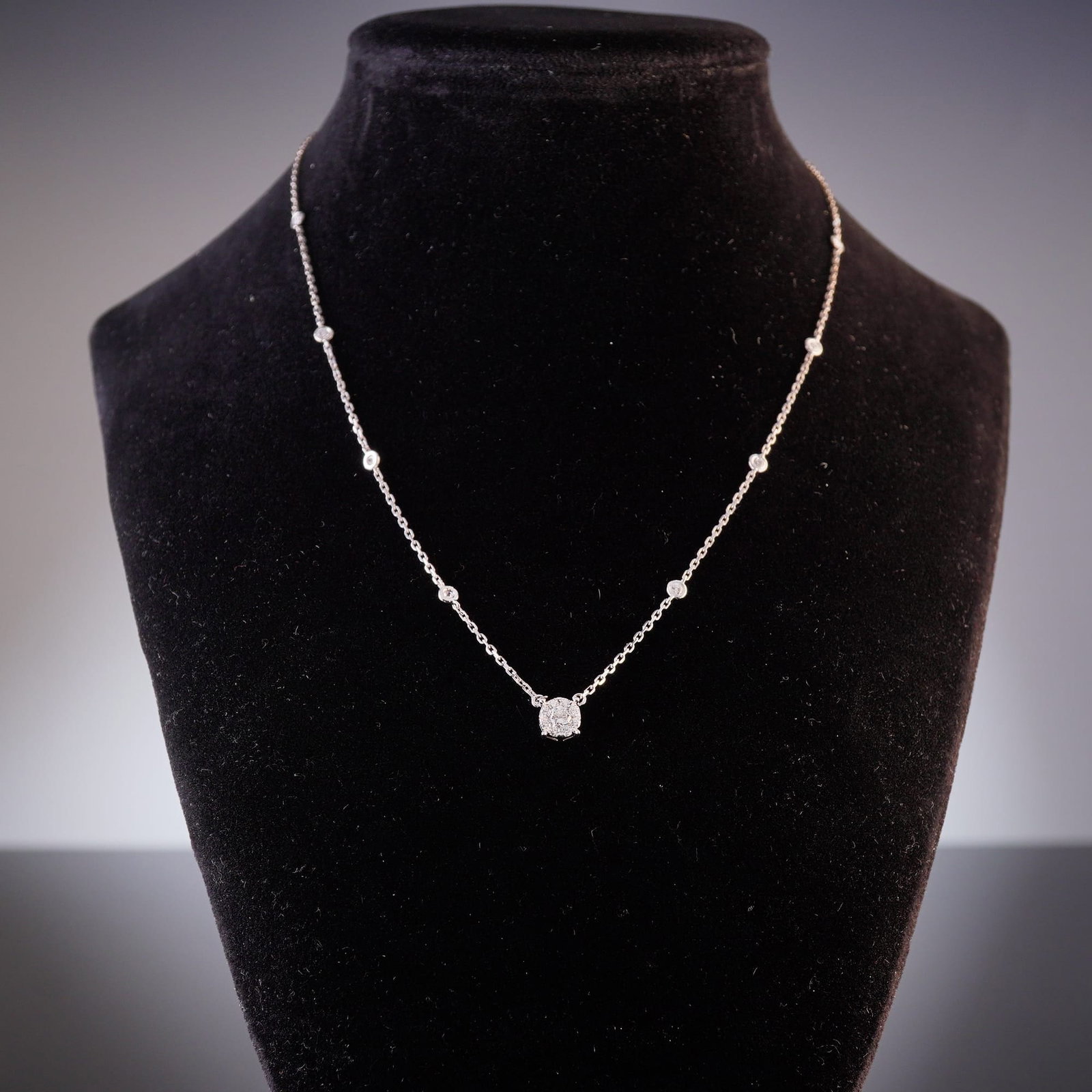 14K White Gold and 0.60ctw Round Diamond Station Necklace: A contemporary 14K white gold diamond station necklace featuring a central circular cluster pendant set with multiple round brilliant-cut diamonds. The reverse of the central pendant is finished with