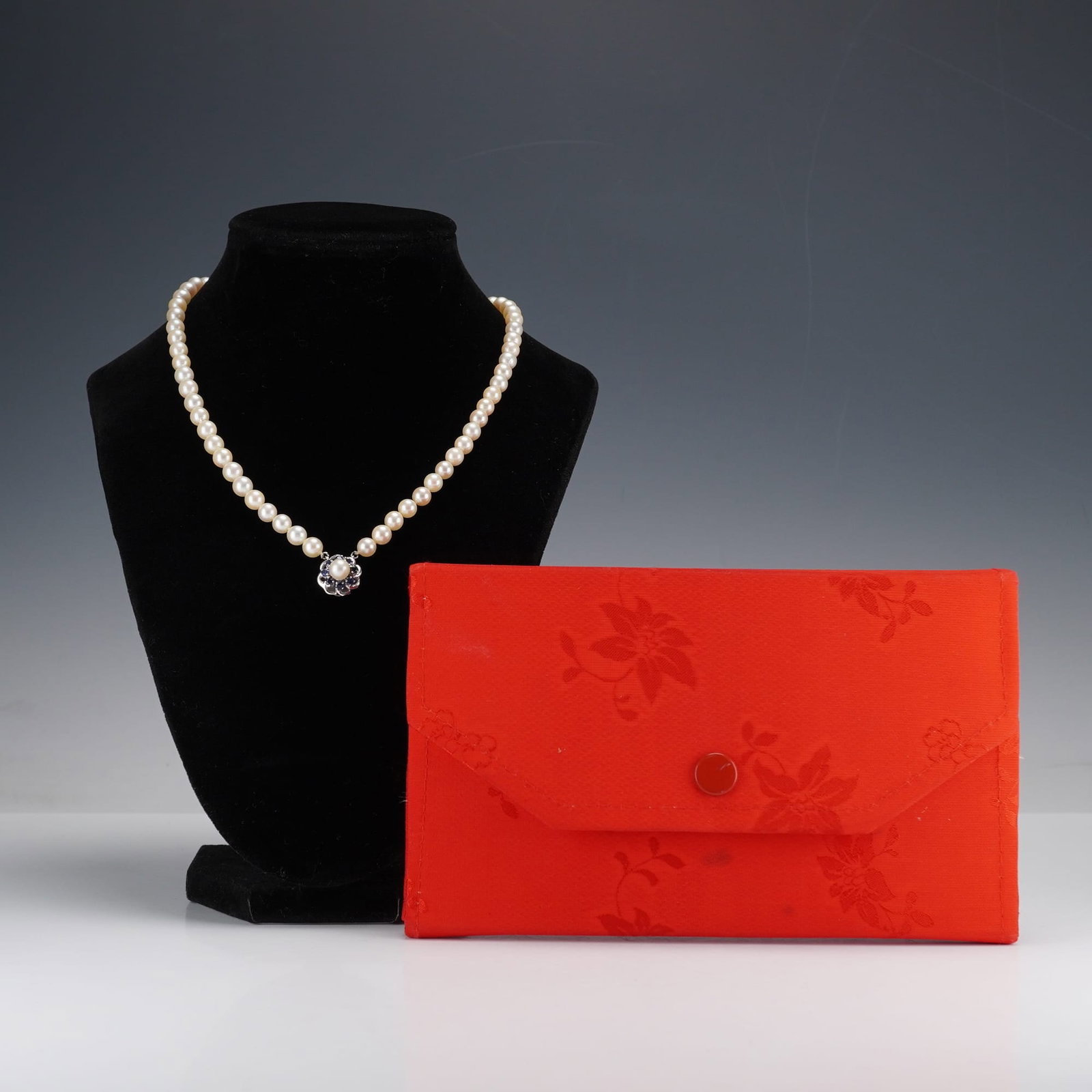 Cultured Pearl Necklace w/ 14K White Gold & Blue Stones Clasp: A single-strand cultured pearl necklace with a 14K white gold and sapphire clasp, presented in its original case by Man Yue Jewelry Hong Kong. The necklace features uniformly sized, individually knott