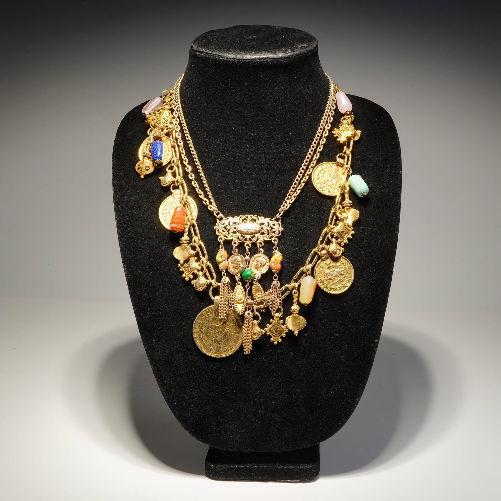 2pc Yellow Gold-Tone Charm and Pendant Link Chain Necklaces: Two gold-tone costume chain necklaces featuring an eclectic assembly of charms and beads. One necklace consists of an oval link chain supporting a variety of suspended elements, including large circul