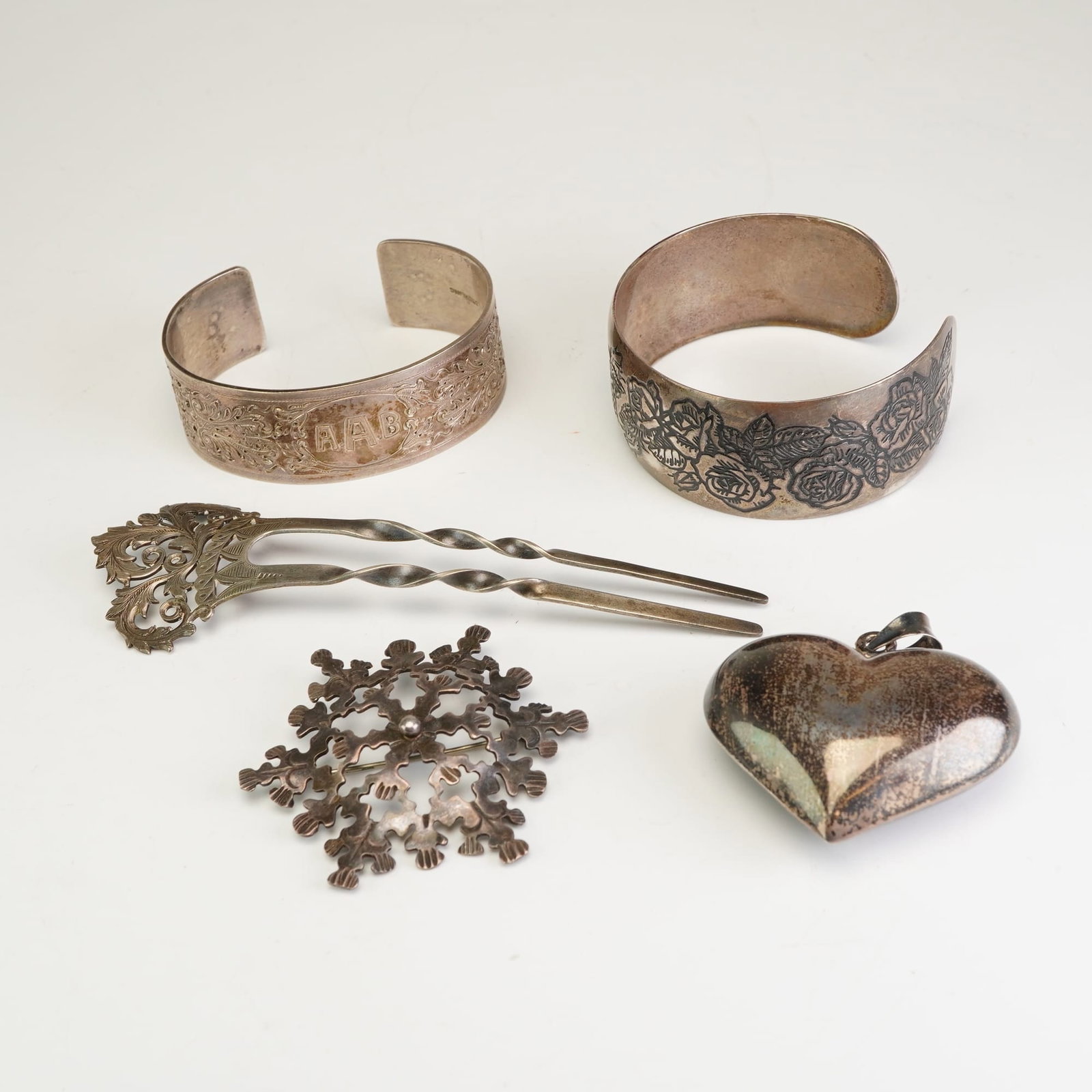 5pc Sterling Silver including Napkin Rings, Snowflake Brooch, Heart Pendant, and Hair Pin: This collection features five items crafted from sterling silver. The lot includes a two-pronged hair fork with twisted tines and an ornate openwork foliate head, hallmarked STERLING SILVER and number