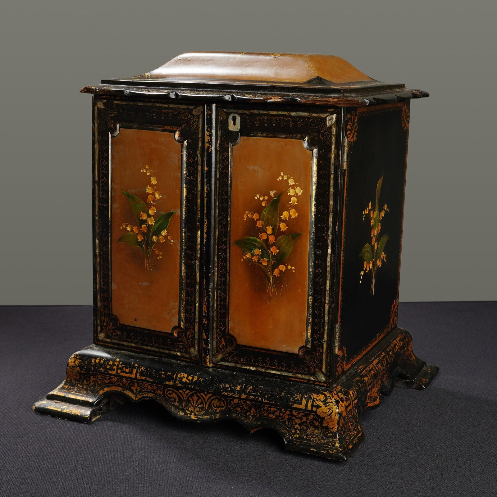Victorian Style Lacquered Papier-Mache Jewelry Cabinet: This Victorian inspired lacquered jewelry box/cabinet is decorated with yellow flowers in a Lily of the Valley motif against a black ground. The structure features a domed, hinged lid and twin front d