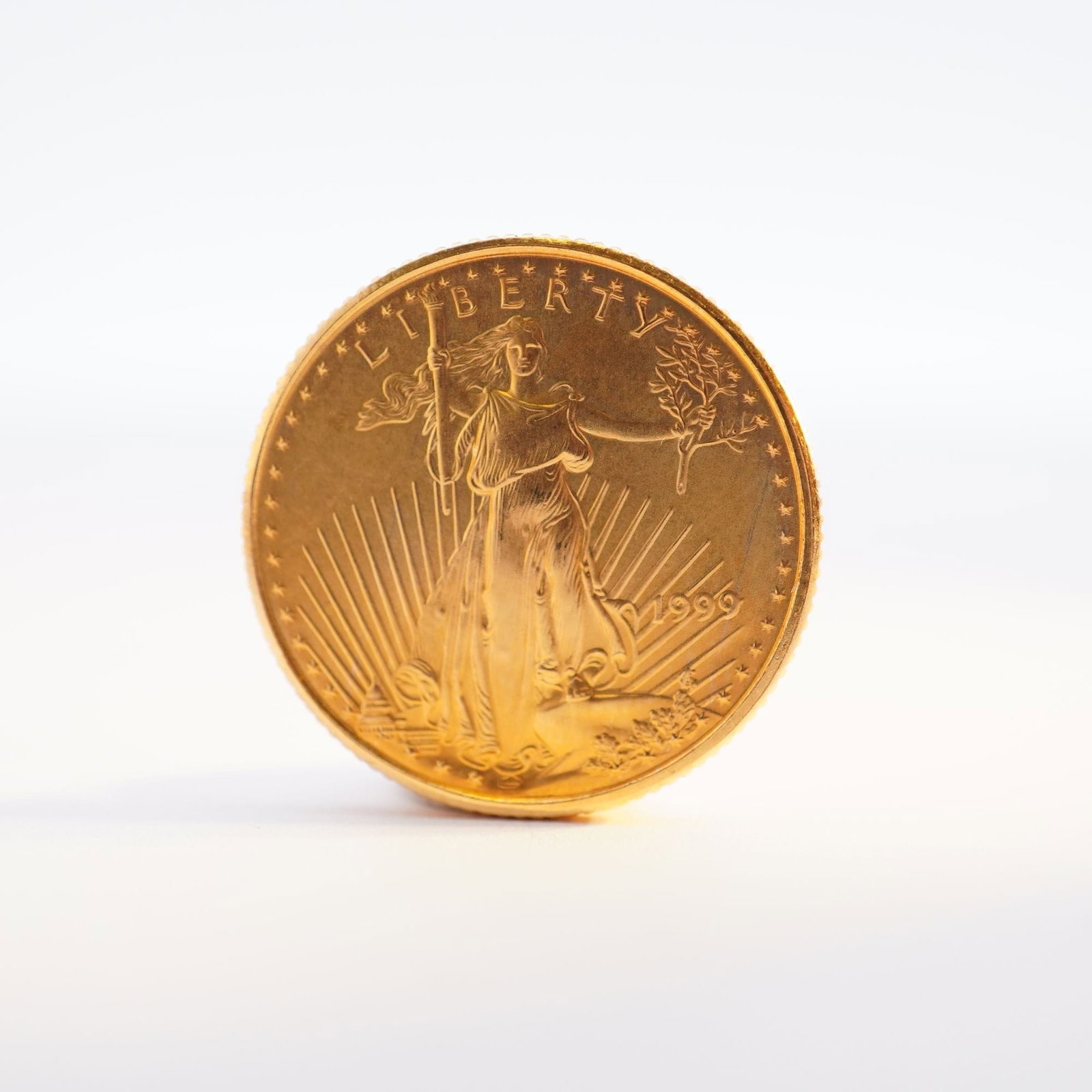 1999 1/10 Fine Gold $5 American Gold Eagle Coin: Minted by the Philadelphia Mint. The obverse side depicts an effigy of Liberty with the date to the right. The reverse side depicts an eagle in flight above a nest of birds with the country name at th