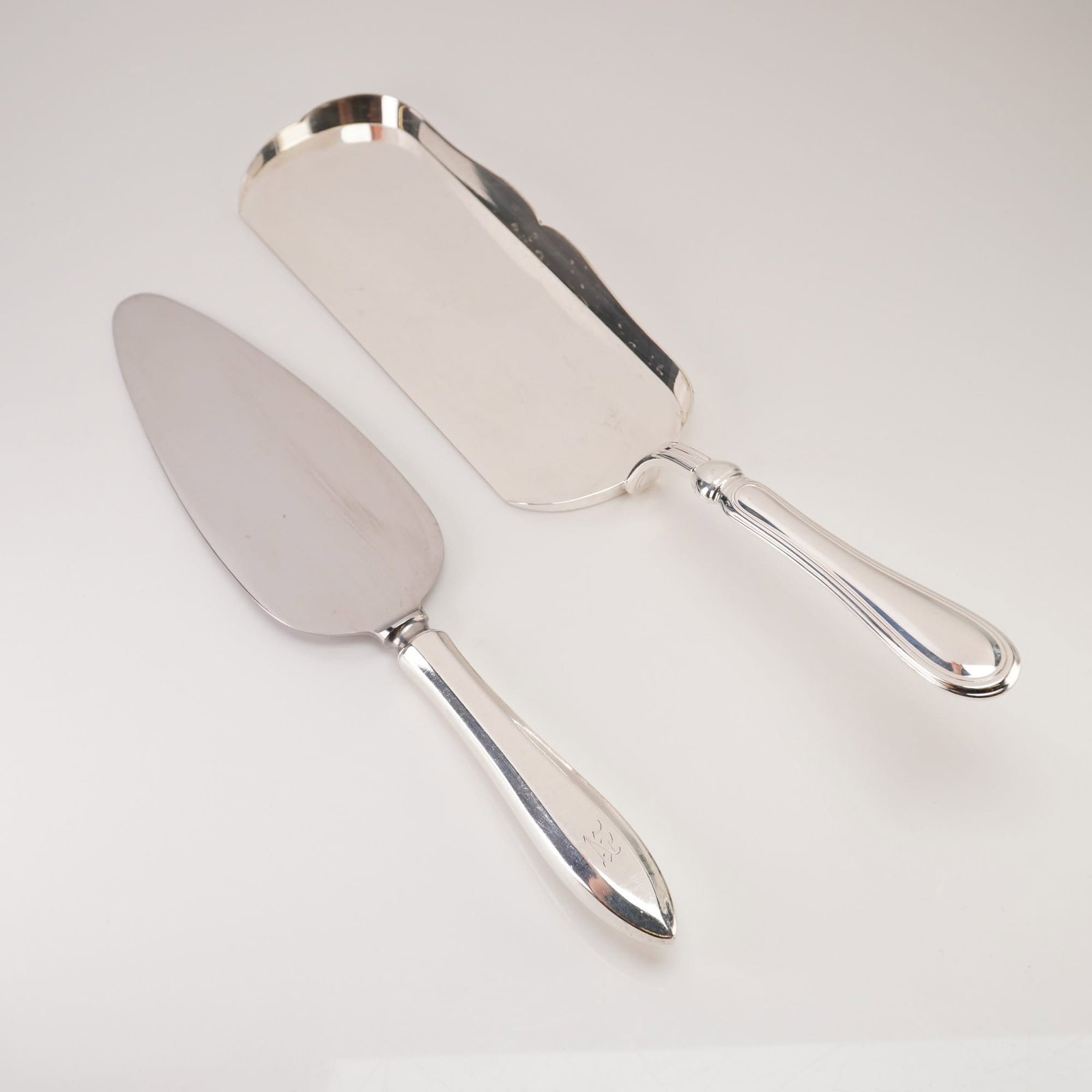 Ravinet d'Enfert and Community Pirouette, Crumb Scraper and Cake Server, Silverplate and Sterling: A pair of silver serving pieces. The first is a French silverplate crumb scraper by the silversmithing firm Ravinet d'Enfert (Louis Ravinet and Charles d'Enfert), featuring a classic double-threaded h