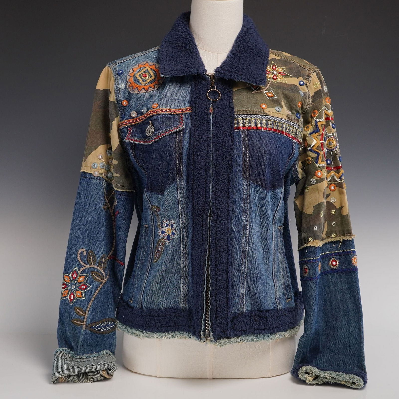 Contemporary Desigual Patchwork Denim Jacket with Embroidery and Fleece Detailing: This contemporary women's jacket by Desigual, produced circa 2018, features a complex patchwork construction with a bohemian-inspired aesthetic. The garment is crafted from multiple panels of blue cot