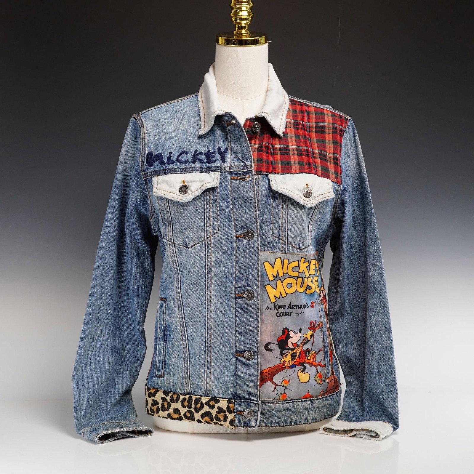 Contemporary Desigual Patchwork Denim Jacket, Mickey Mouse Theme: This contemporary trucker-style denim jacket by Desigual features an eclectic patchwork design with vintage-inspired Mickey Mouse motifs. Produced circa 2019, the garment is crafted from medium-wash b