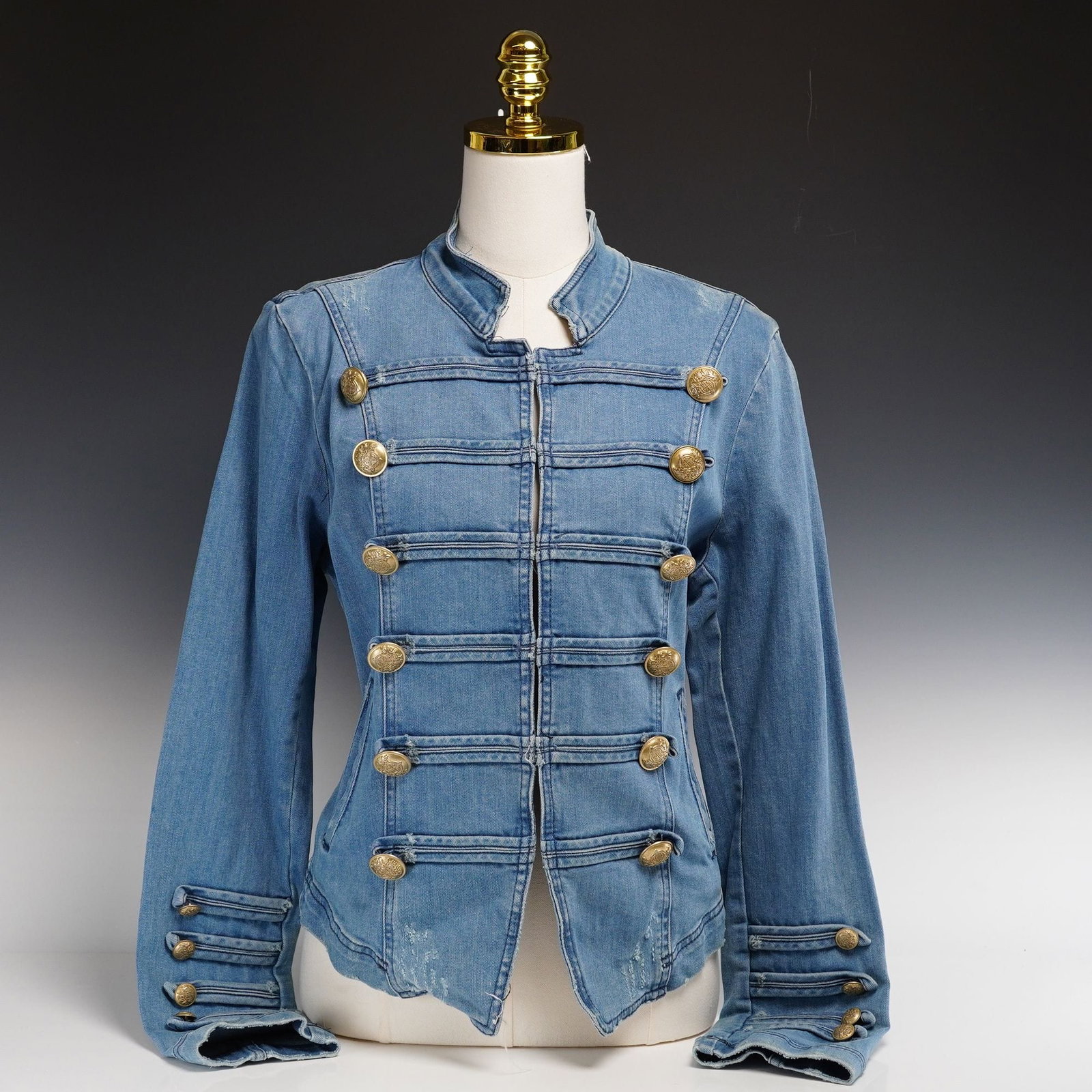 Contemporary Free People Fitted Military Denim Jacket with Gold-Tone Crest Buttons: This contemporary fitted military denim jacket by Free People is crafted from a light-wash indigo blue cotton blend. The garment features a hussar-inspired aesthetic with a tailored feminine silhouett