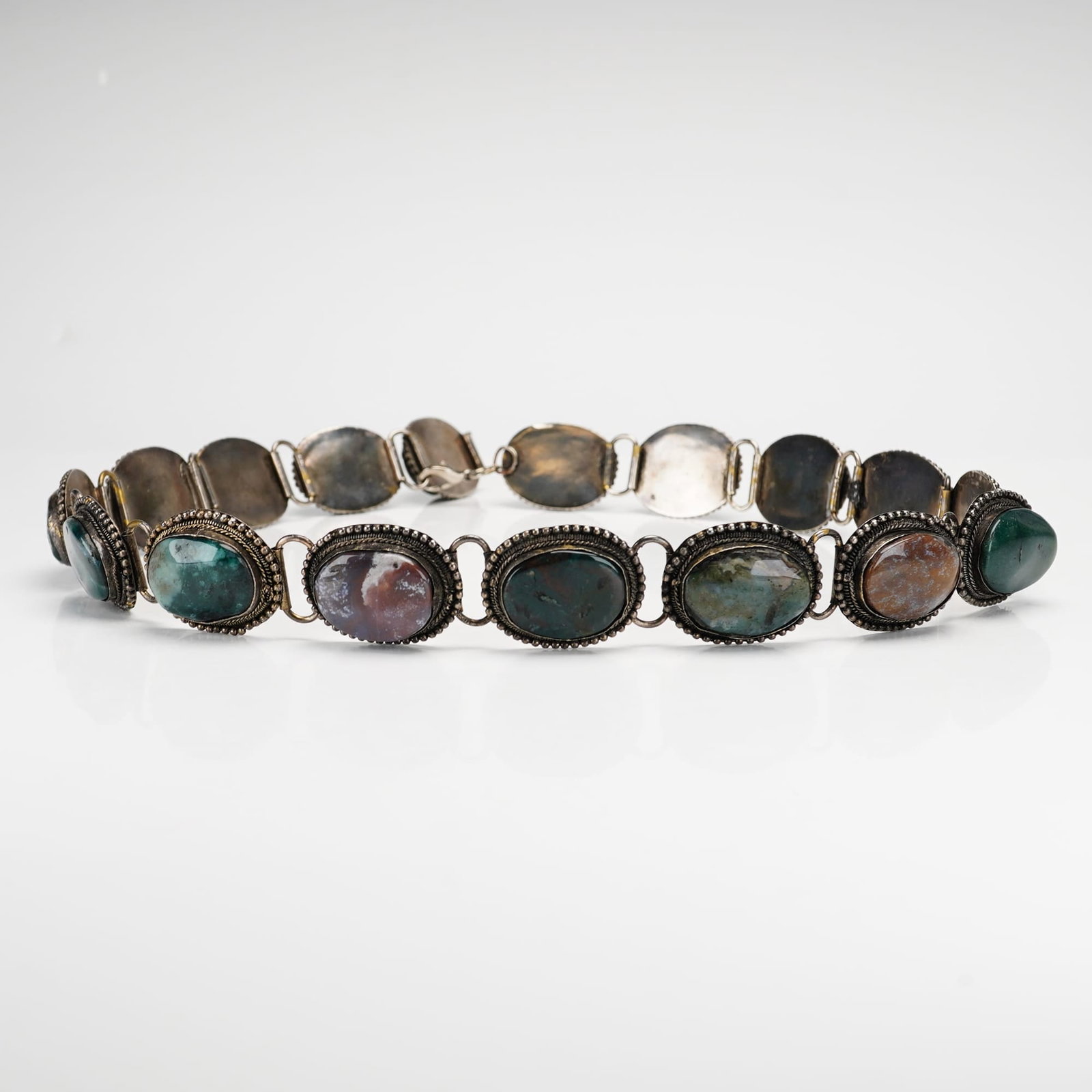 Natural Agate and Jasper Cabochon Stones Silver-Metal Link Belt: A silver-toned link belt made of natural cabochon stones. The piece is composed of multiple oval-shaped stones, including various types of agate and jasper in a palette of green, red, and earth tones.