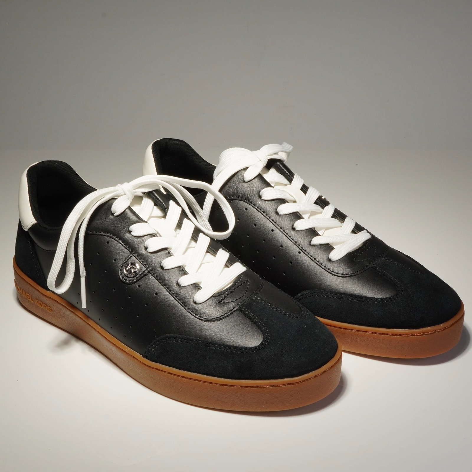 Michael Kors Women's Scotty Sneakers: A pair of Michael Michael Kors Scotty low-top lace-up sneakers featuring black leather uppers with tonal suede overlays at the toe and heel. The construction includes white laces and a contrasting whi