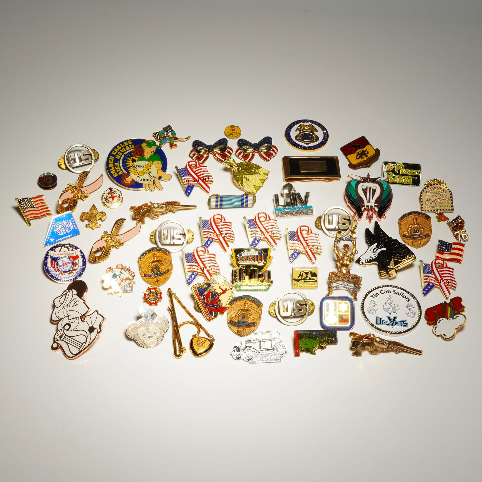 Commemorative Collection of Lapel Pins and Tie Bars: This lot comprises an extensive collection of over 40 enameled lapel pins, tie bars, and small commemorative metal pieces. The collection features a wide array of subjects including patriotic 9/11 Nev