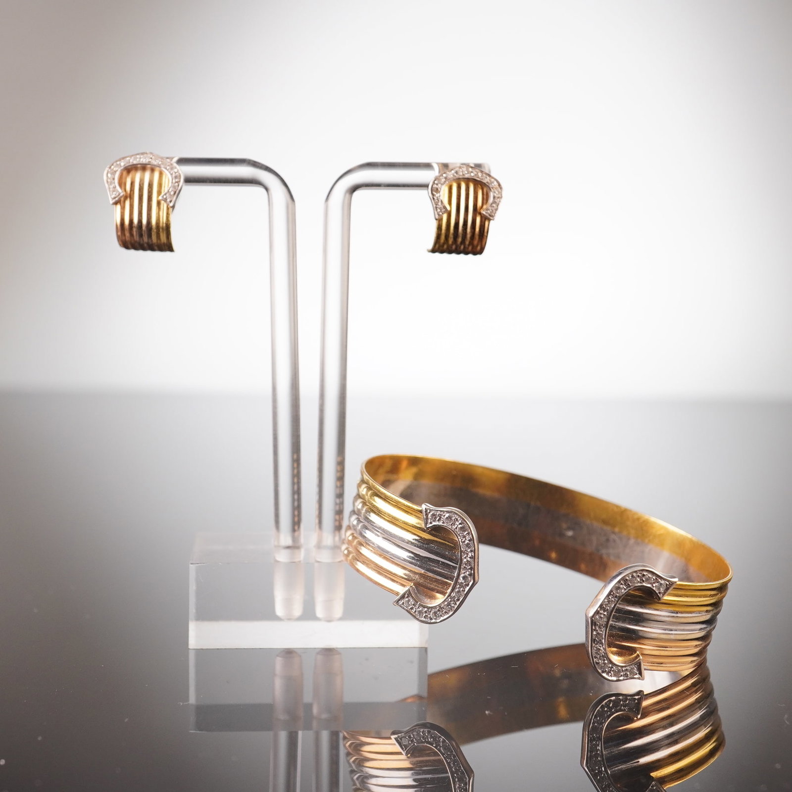 18K Tri-Color Gold Diamond Double C Open Cuff Bracelet and Earrings: This open cuff bracelet is crafted from yellow, white, and rose gold, featuring C's on each end that are set with diamonds. It comes with a pair of matching earrings in yellow and white gold, each wit