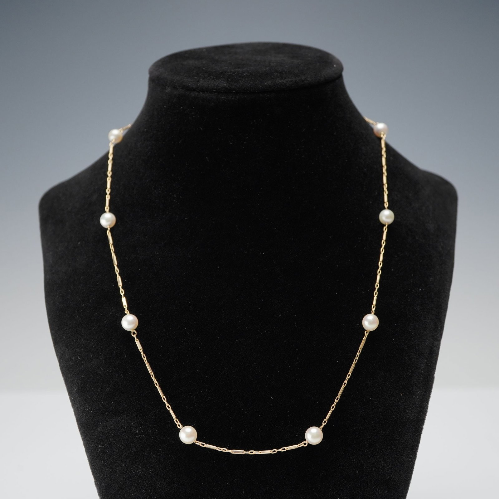 14K Gold Cultured Pearl Station Necklace: Necklace featuring evenly spaced cultured pearls set along a 14K gold chain. The design alternates polished gold links with round pearls, creating balanced intervals throughout the strand. Clasp stamp
