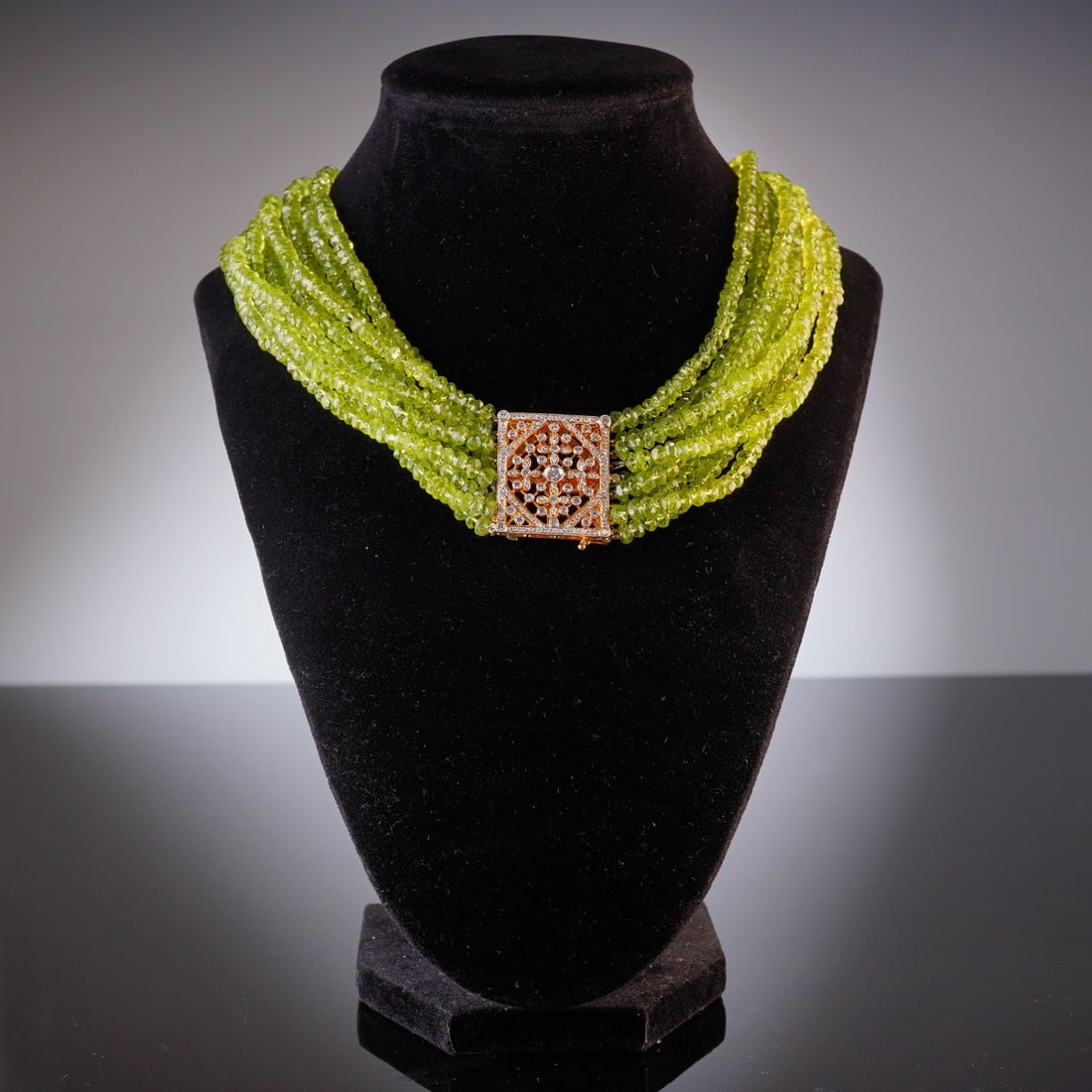 14K Yellow Gold Peridot and Diamond Multi-Strand Necklace: This 14K yellow gold peridot and diamond necklace is composed of multiple strands of faceted, translucent lime-green peridot beads. The strands are gathered by a square 14K yellow gold box clasp featu