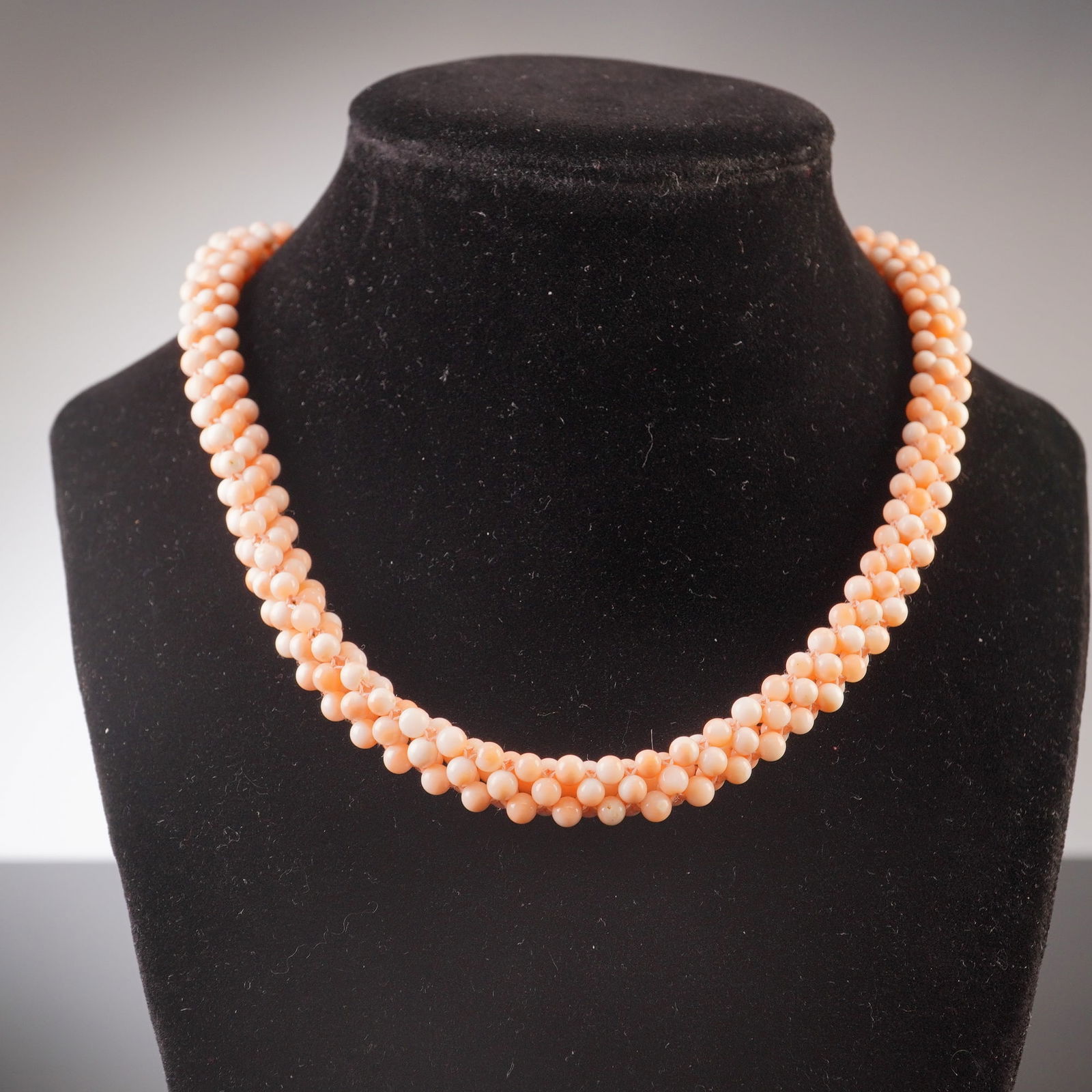 18K Gold and Coral Beads Multi-Strand Torsade Necklace: Multi-strand necklace featuring angel skin coral beads woven into a thick, torsade style, finished with a polished 18K gold clasp. Stamped 18K. Dimensions16"L x 0.25"W Weight35.6 g.