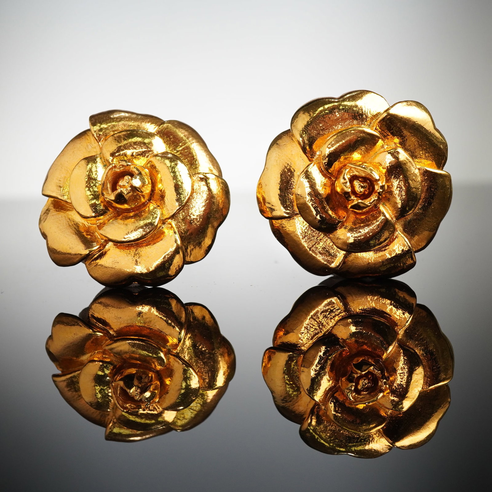 2pc CHANEL Paris Gold-Tone Camellia Brooches: This offering consists of two Chanel brooches featuring the iconic camellia floral motif, often associated with the brand's classic designs. Each piece is crafted in a yellow-gold tone, consistent wit
