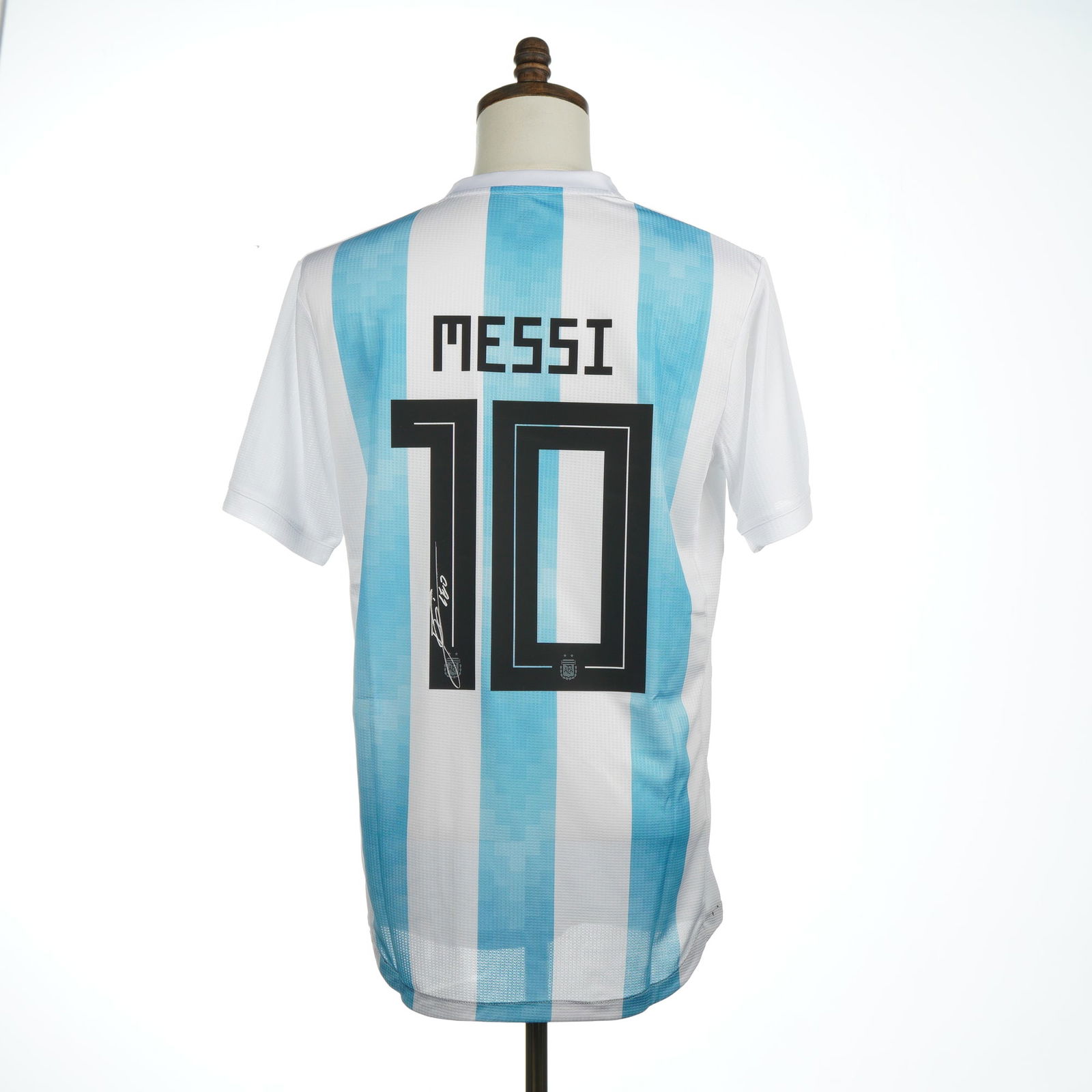 Lionel Messi Signed Argentina National Team 2018 Replica Jersey COA: A signed Argentina National Team replica home soccer jersey, model year 2018, signed by Lionel Messi. The jersey is constructed of white and light blue vertically striped fabric. The front features th