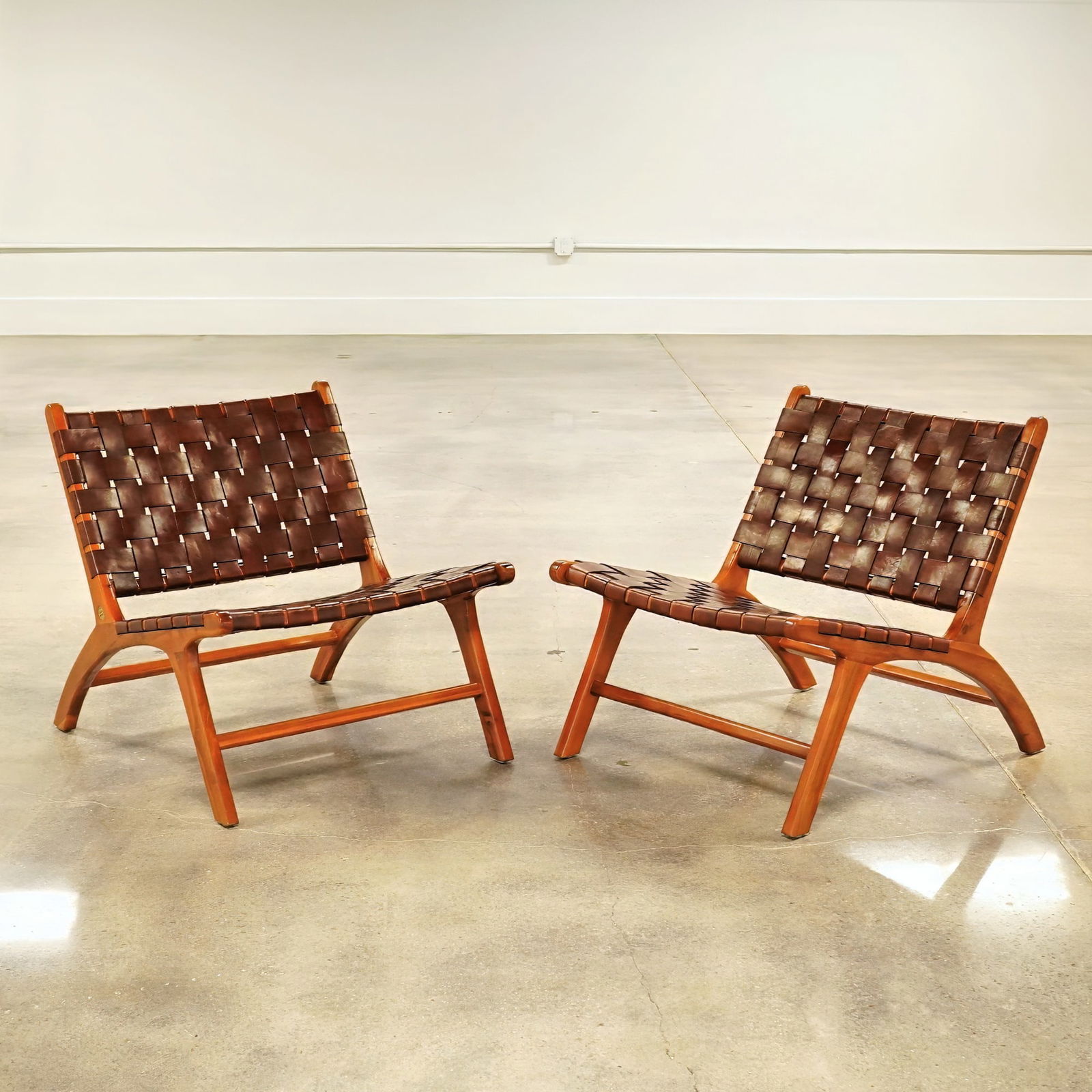 Pair of Olivier De Schrijver Teak and Woven Leather Relax Chairs, Miami: A pair of Olivier De Schrijver relax chairs named Miami, featuring frames constructed of teak wood. The seats and backs are composed of natural brown leather straps in a woven pattern, secured to the