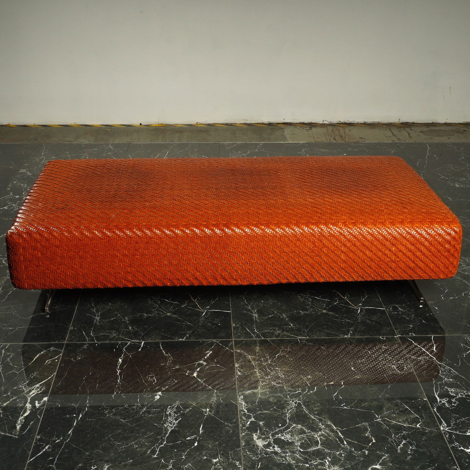 Flexform Filicudi Woven Hide Leather Ottoman: This contemporary Italian large ottoman, manufactured by Flexform, features a sturdy, low-profile rectangular frame. The piece is supported by two architectural sled-style legs made of brushed metal,