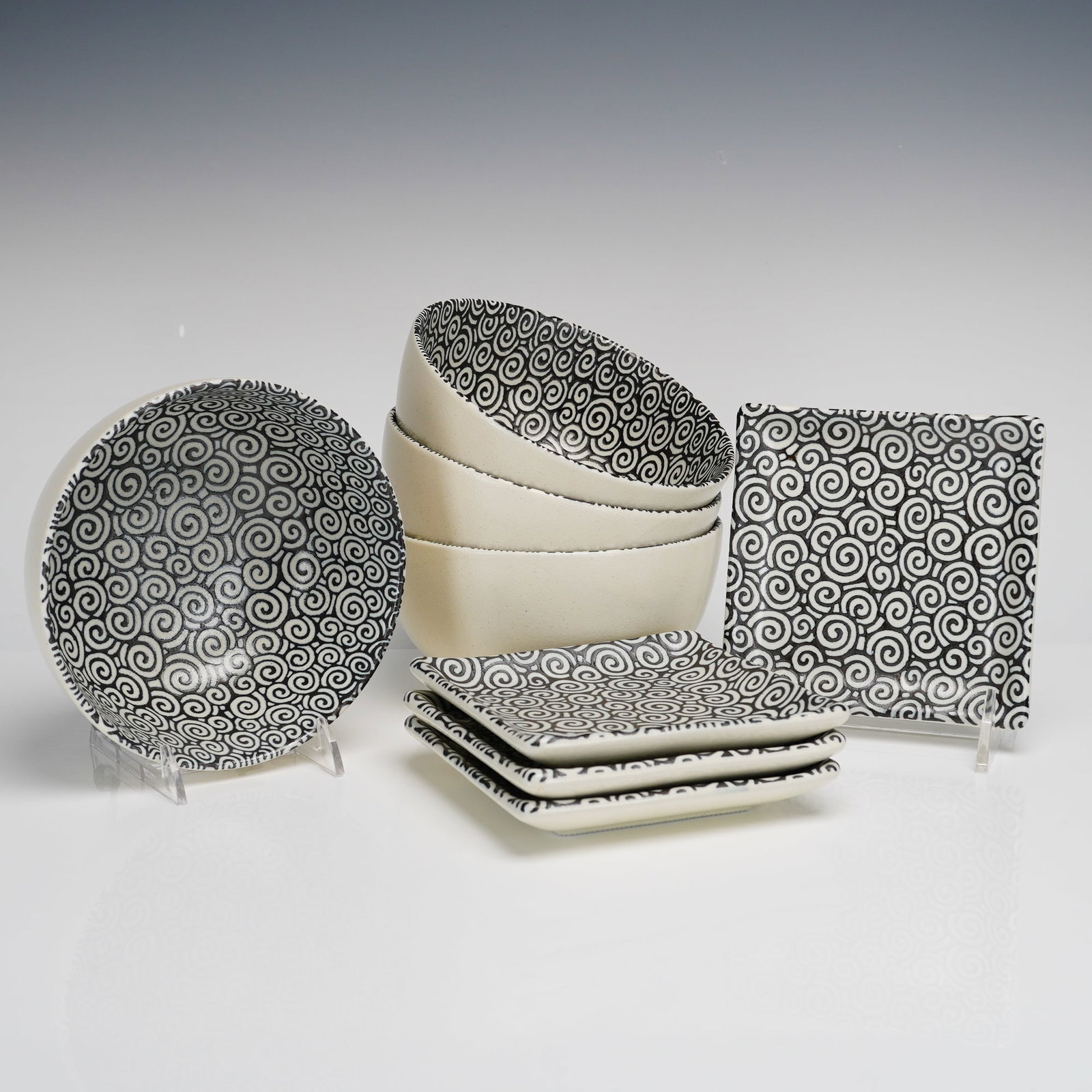 8pc. Kanesada Sound Collection Ceramic Rice Bowls and Sushi Plates: The group consists of four round bowls and four-square plates. Each piece features a black and white interlocking spiral pattern on the interior of the bowls and the upper surface of the plates, with