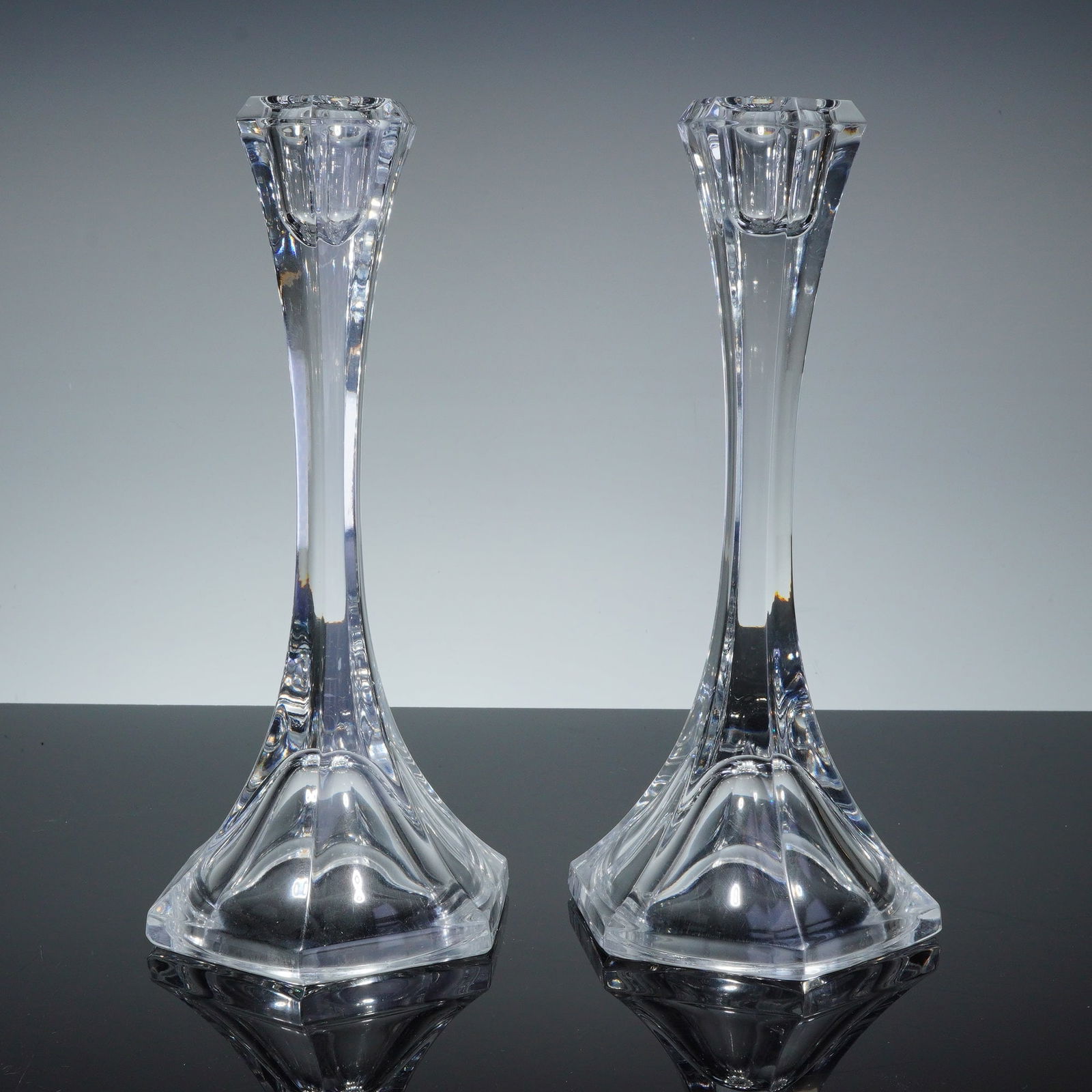 Pair of Mikasa Lead Crystal Candlestick Holders: A pair of lead crystal candlesticks featuring fluted stems that flare into hexagonal bases. Each base features a molded geometric pattern on the underside. The tops are finished with faceted hexagonal