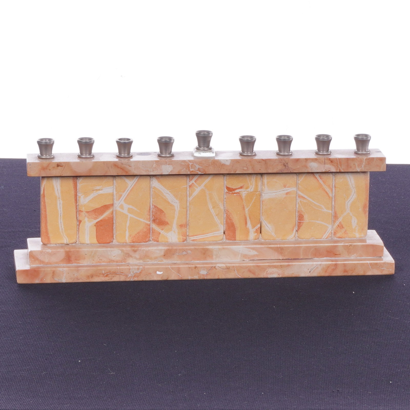 Judaica Polished Jerusalem Stone & Marble Hanukkah Menorah: This modern Hanukkiah (Hanukkah menorah) is crafted from polished Jerusalem stone, a variety of veined marble, displaying a natural color palette of peach, cream, and orange with white veining. The ar