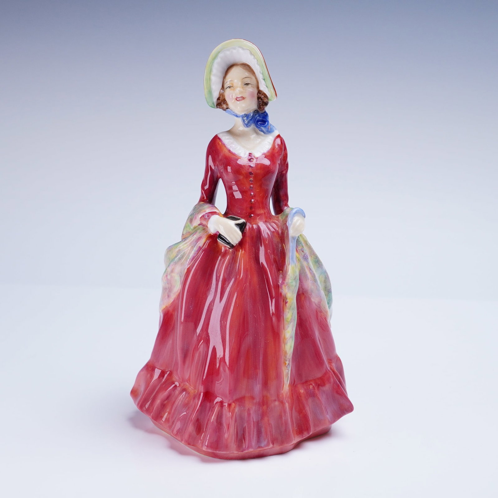 Royal Doulton Bone China Figurine Sabbath Morn HN 1982: A single glazed bone china figurine manufactured by Royal Doulton, titled "Sabbath Morn," model number HN 1982. The figure depicts a Victorian-era woman dressed in a long, ruffled red gown, carrying a