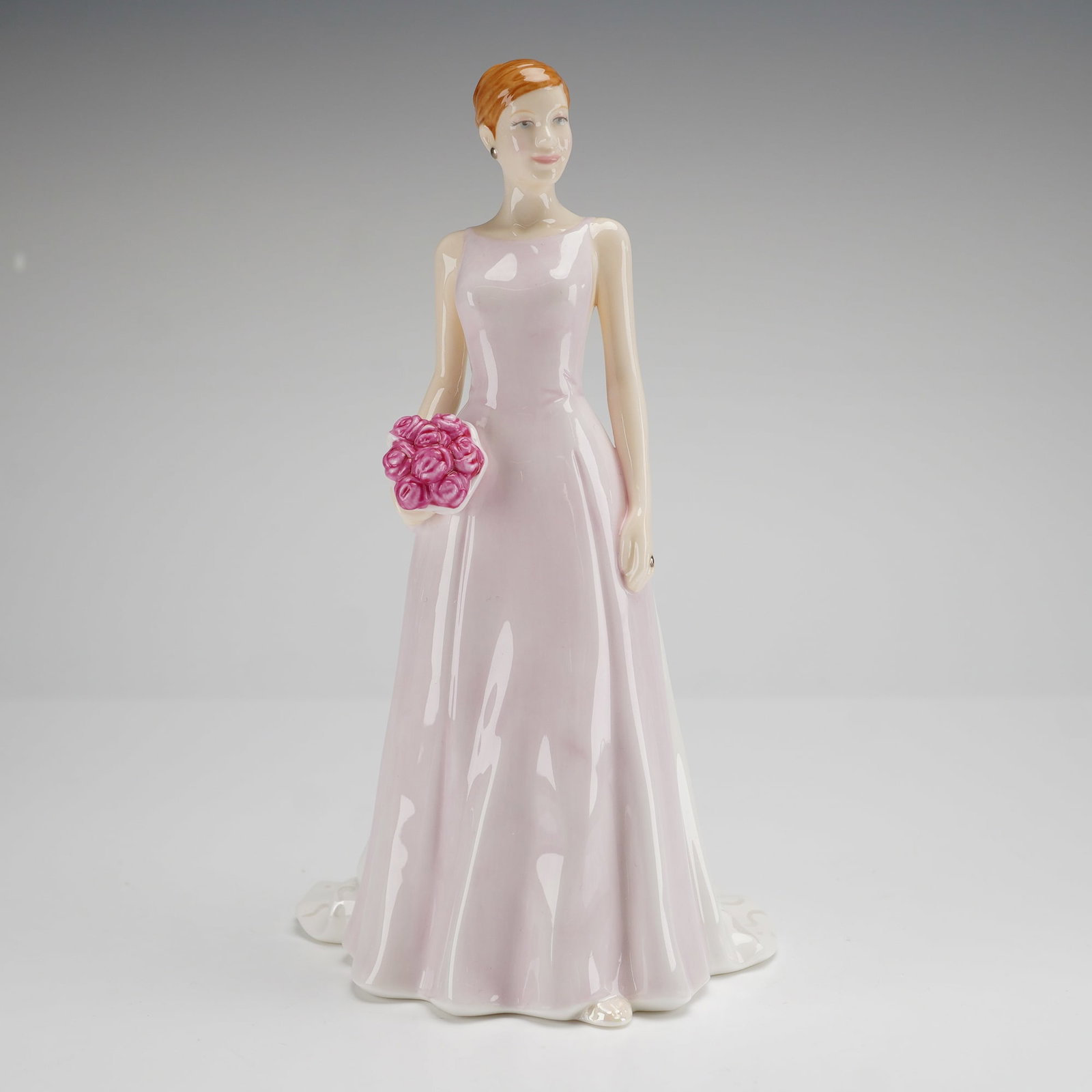 Royal Doulton Rose Bouquet HN 4796 Petite Figurine: A Royal Doulton Rose Bouquet HN 4796 petite figurine from the Pretty Ladies series. This bone china figure is hand-made and hand-decorated, depicting a standing woman with auburn hair in a pale lavend