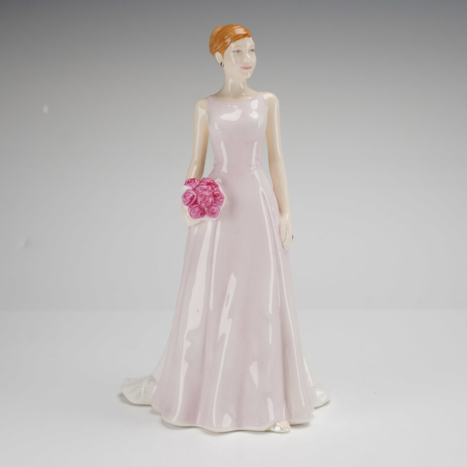 Royal Doulton Rose Bouquet HN4796 Petite Figurine: A Royal Doulton bone china Rose Bouquet HN4796 petite figurine from the Pretty Ladies collection. This hand-made and hand-decorated piece depicts a standing female figure with reddish-blonde hair styl