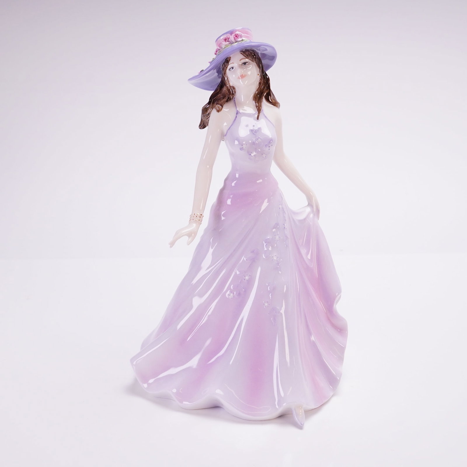 Coalport Ladies of Fashion Figurine, Emma: A Coalport figurine from the Ladies of Fashion series, modeled by Jack Glynn. The figure is depicted in a walking pose wearing a lavender and lilac halter-style gown with floral accents and a wide-bri