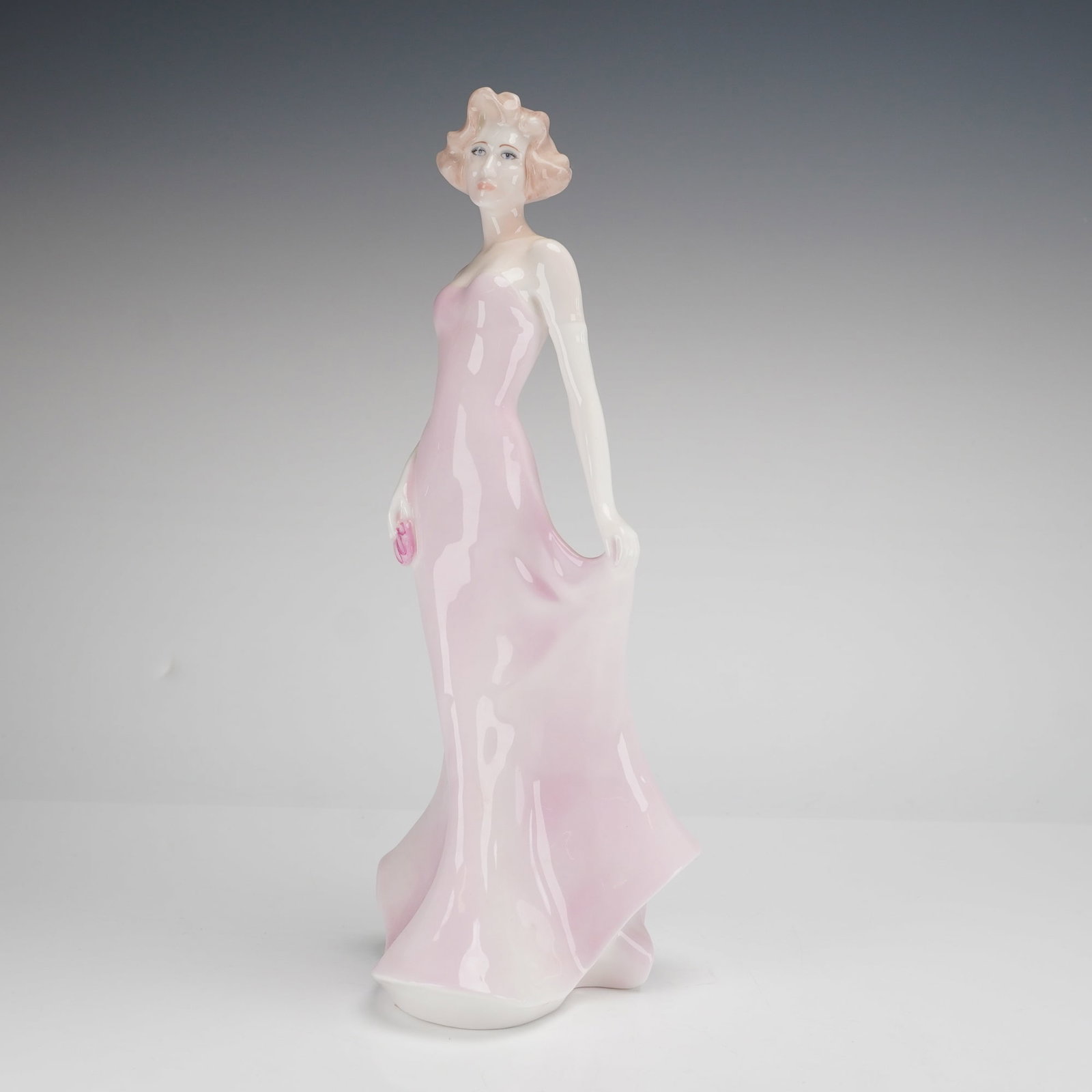 Coalport Silhouettes Collection Figurine, Olivia: A hand-decorated Coalport bone china figurine titled Olivia from the Silhouettes collection. The figure is depicted in a floor-length strapless pale pink gown while holding the hem of the dress. The f