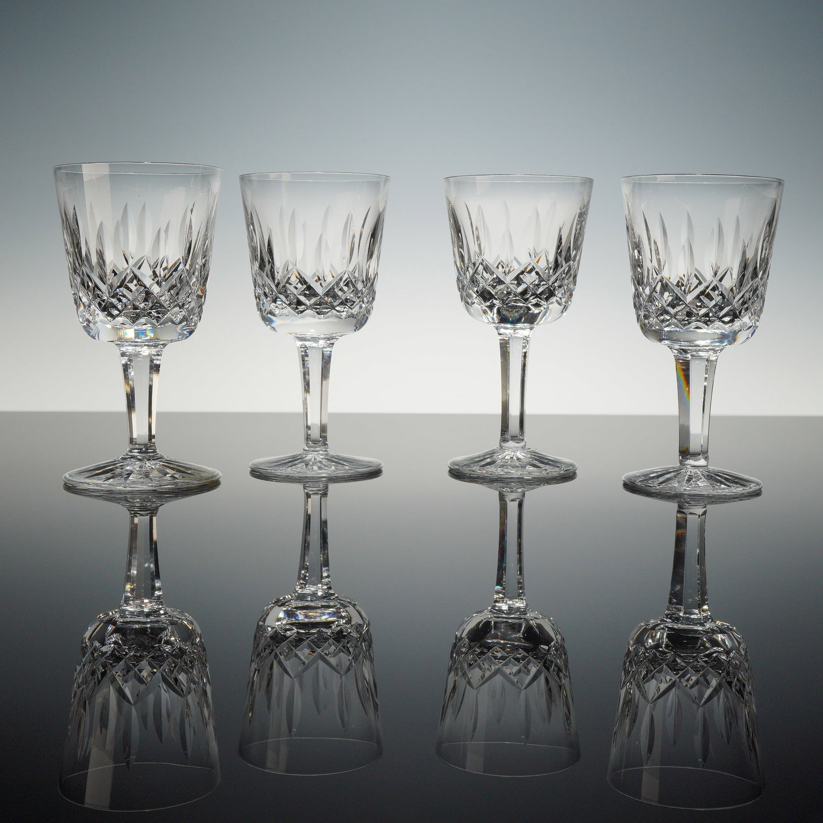 4pc Waterford Lismore Pattern Crystal Wine Glasses: A set of 4 glasses manufactured by Waterford Crystal in the iconic Lismore pattern. Each piece is crafted from fine lead crystal, featuring a bowl decorated with deep diamond cross-hatchings and verti