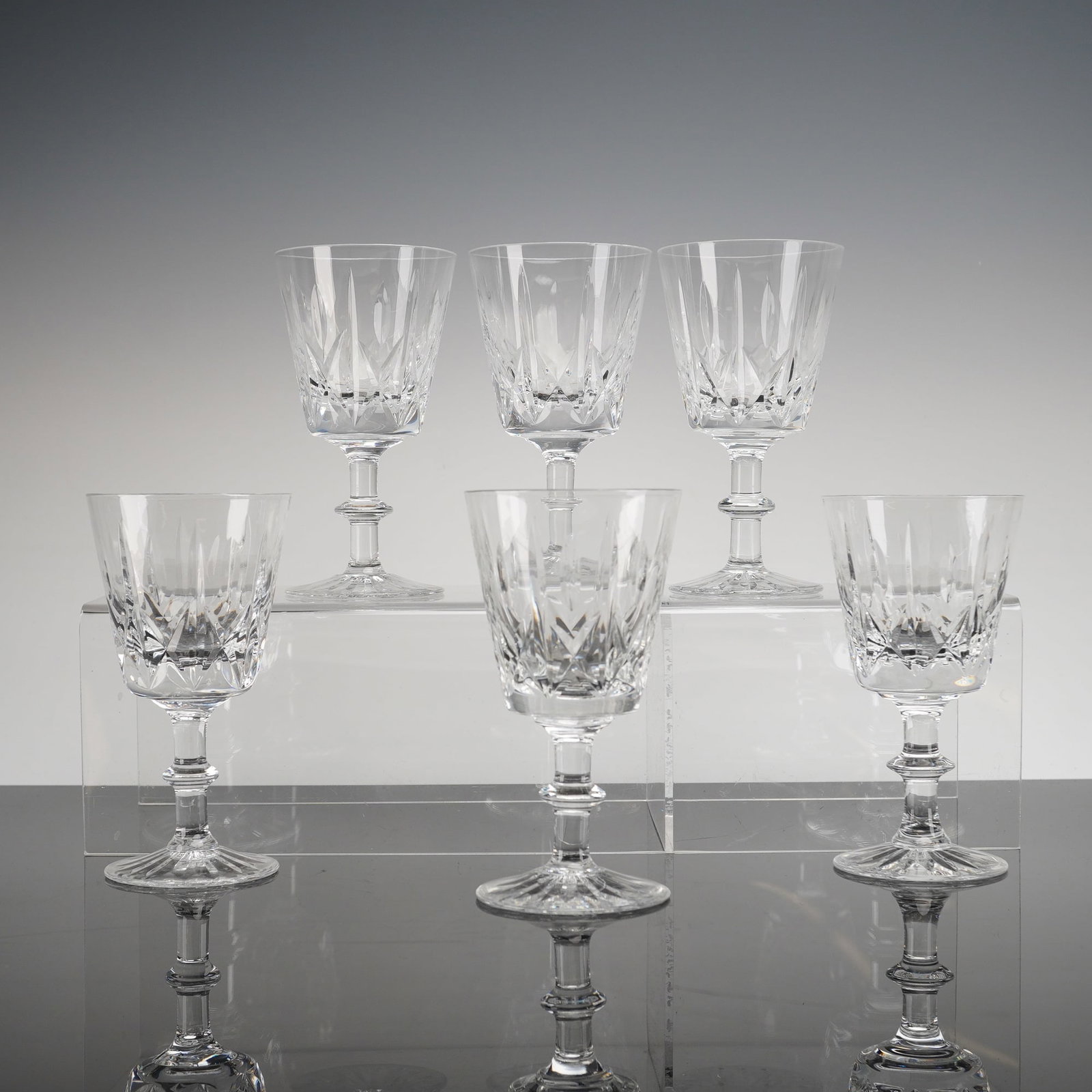6pc Royal Brierley Crystal Ascot Wine Glasses: These wine glasses are executed in clear lead crystal or high-quality glass, featuring deep geometric cutting on the bowl. The cutting includes repeating vertical facets and intersecting diamond motif