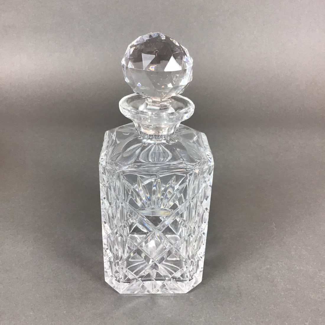 Waterford Lismore Pattern Crystal Square Spirit Decanter: This large quality crystal spirit decanter is produced by Waterford in the Lismore pattern. The piece features a heavy, square-profile body with chamfered corners. The decorative scheme consists of la