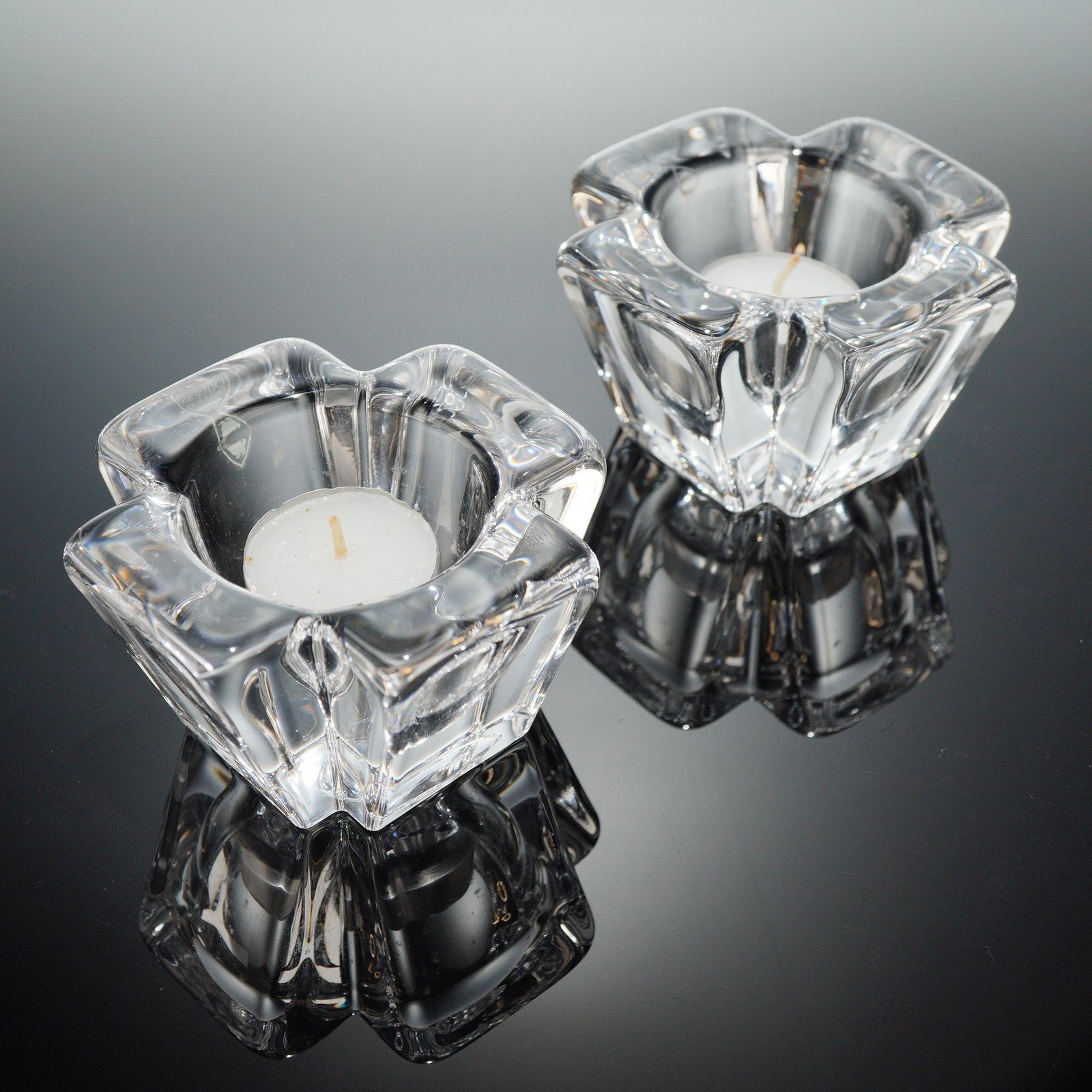 A Pair of Orrefors MAX Crystal Votive Candle Holders: A pair of Orrefors crystal candle holders, identi??ed through web consensus as the MAX patern, often atributed to designer Anna Ehrner. These 2pc crystal candle holders are crafted from heavy clear gl