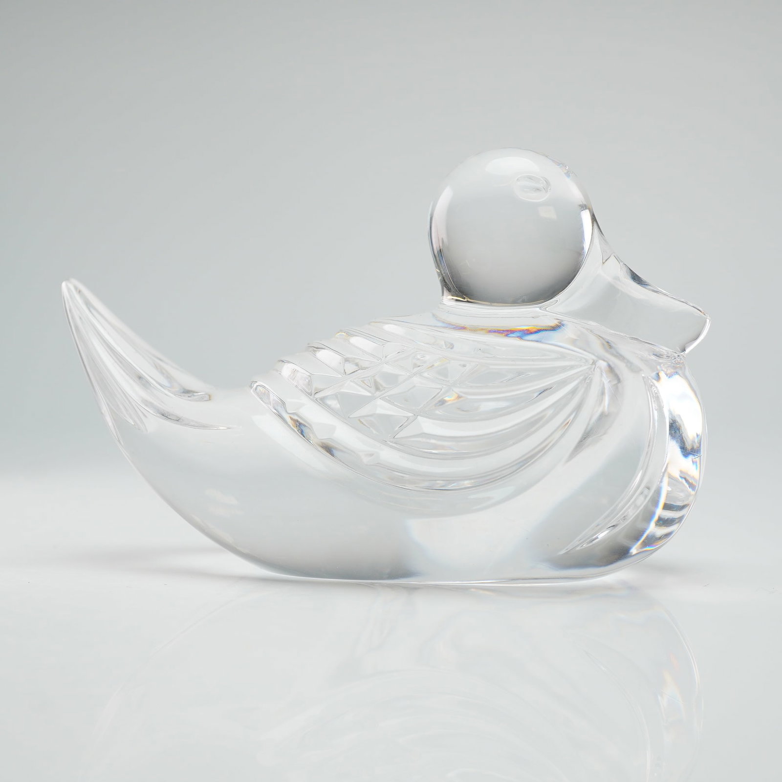 Waterford Crystal Paperweight, Duck: The piece features a stylized form with a smooth, rounded body and head. The wings are decorated with traditional geometric cut patterns. The underside of the base bears an acid-etched Waterford mark.