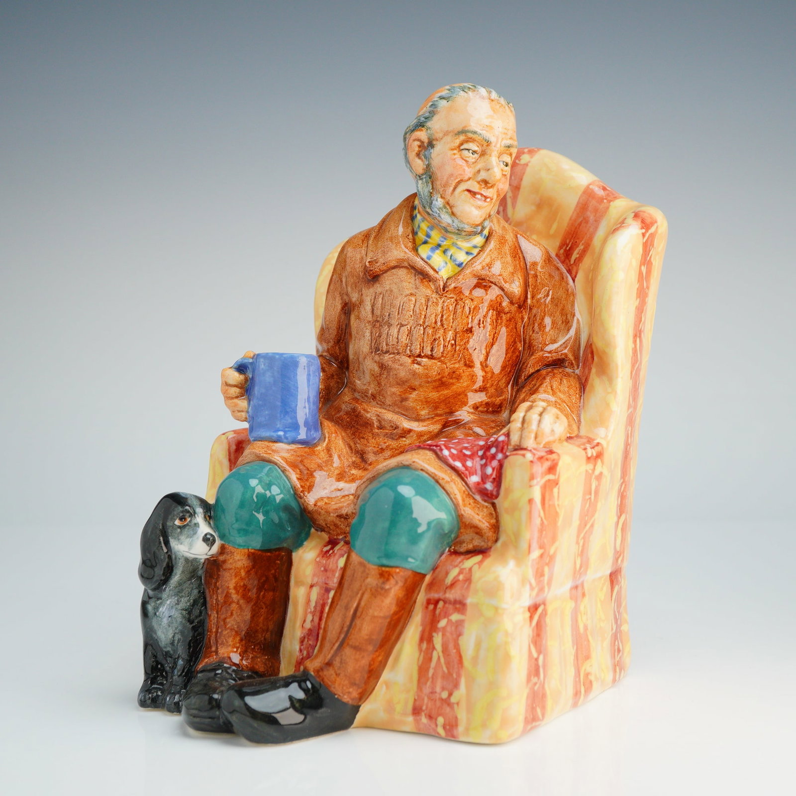 Royal Doulton Figurine Uncle Ned HN2094: This polychrome glazed ceramic figure depicts an elderly man with sideburns seated in a yellow and red striped armchair. He is wearing a brown smock, green breeches, and a checkered neckerchief while