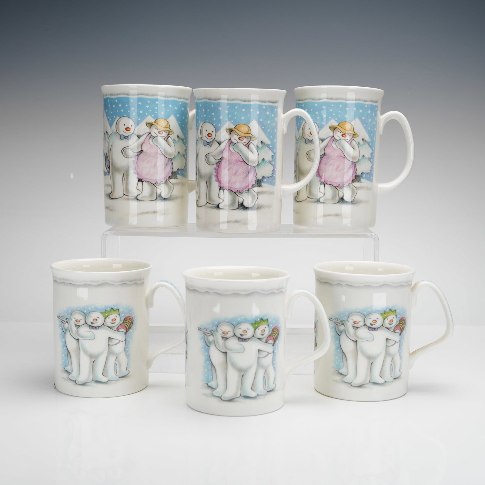 6pc Royal Doulton The Snowman Gift Collection, The Party Mugs: A collection of six Royal Doulton ceramic mugs from The Snowman Gift Collection, featuring The Party pattern. The group includes two distinct vessel forms: three tall tankard-style mugs and three stan