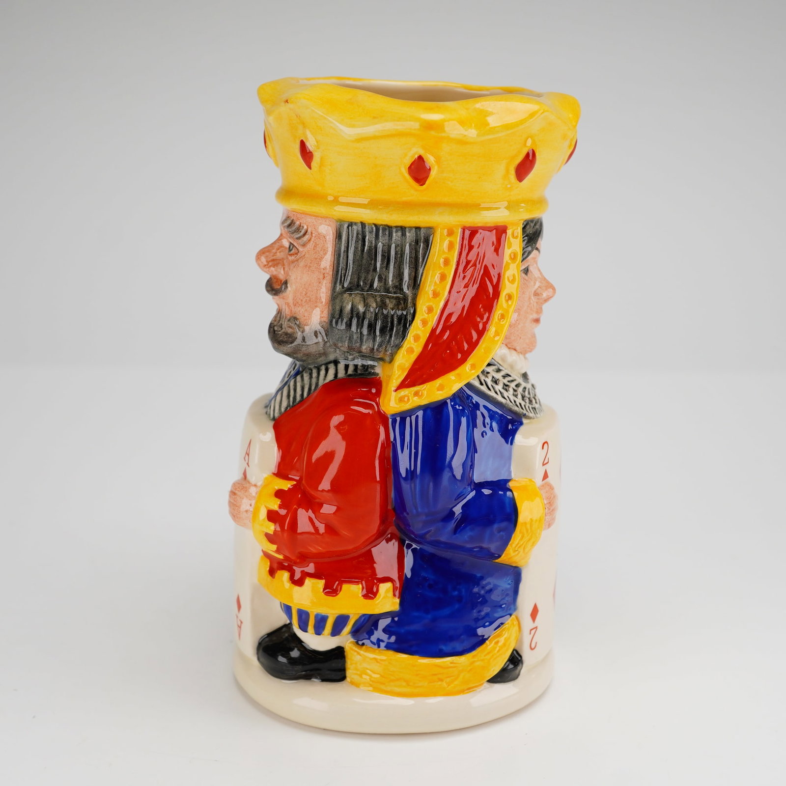 Royal Doulton King and Queen of Diamonds Toby Jug D6969: This Royal Doulton character jug, titled King and Queen of Diamonds (D 6969), is a glazed ceramic piece modeled by Stanley James Taylor in 1994. The two-sided design depicts a bearded king in a red tu